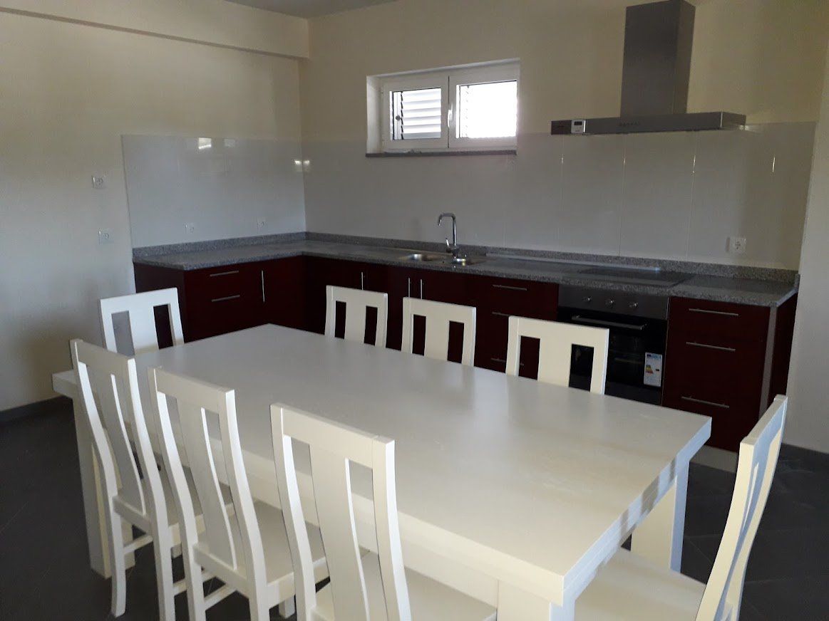 Mesa com cadeiras em madeira pintadas a branco em cozinha bordeaux aplicada pela Jorge Móveis