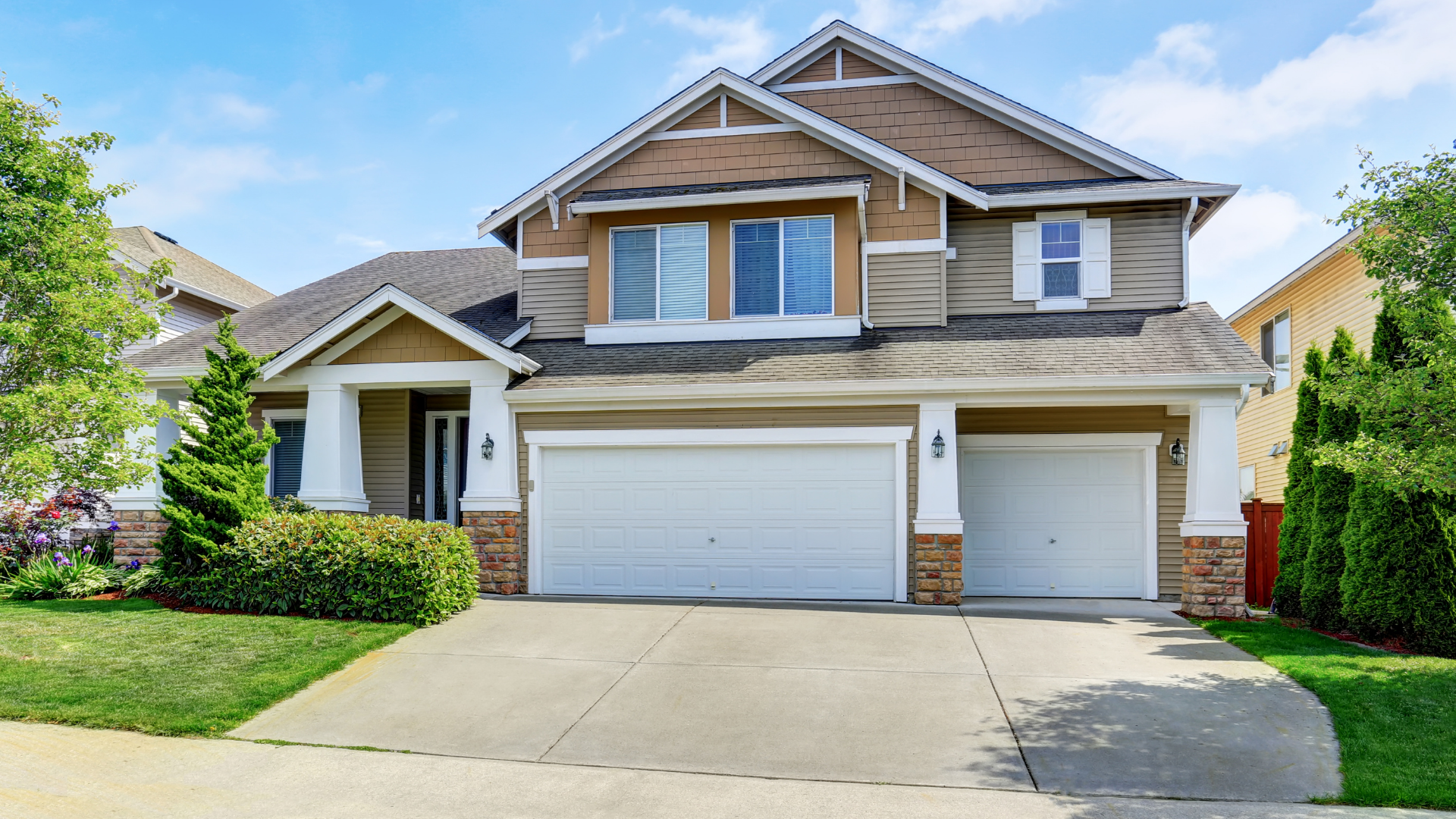 Suburban two-story house with beige siding, three-car garage, and driveway under a blue sky.