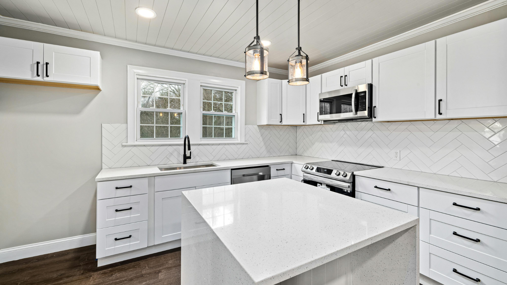 Bright white modern kitchen with island, stainless appliances, and gray tile backsplash