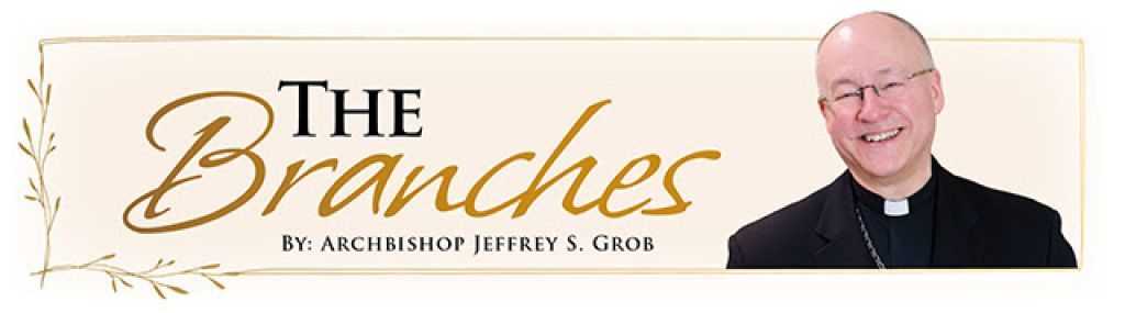 Banner reading “The Branches” with a smiling priest in a black clerical shirt on a light beige background