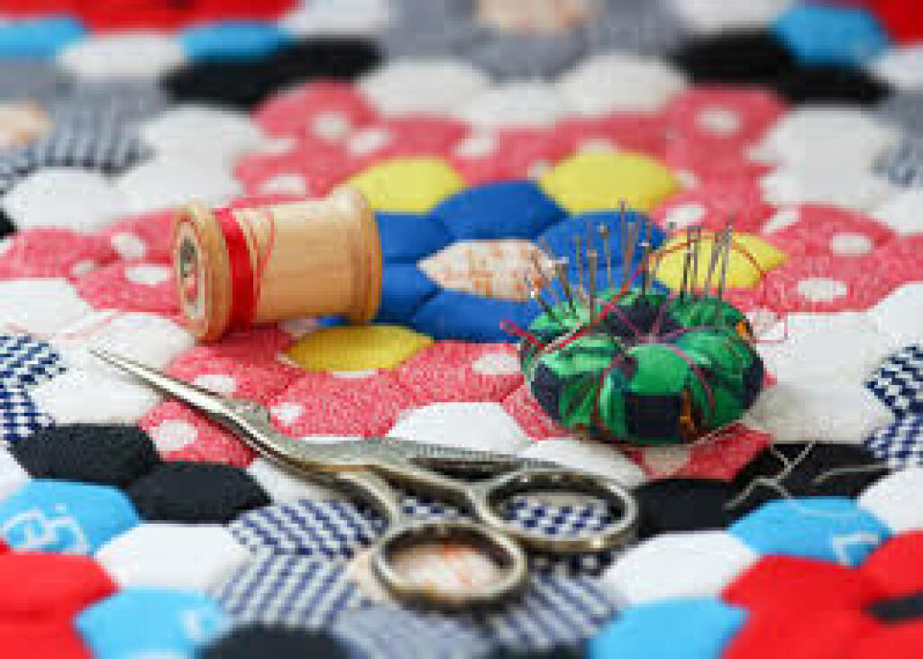 Sewing supplies on patterned fabric: thread spools, pins, and scissors.