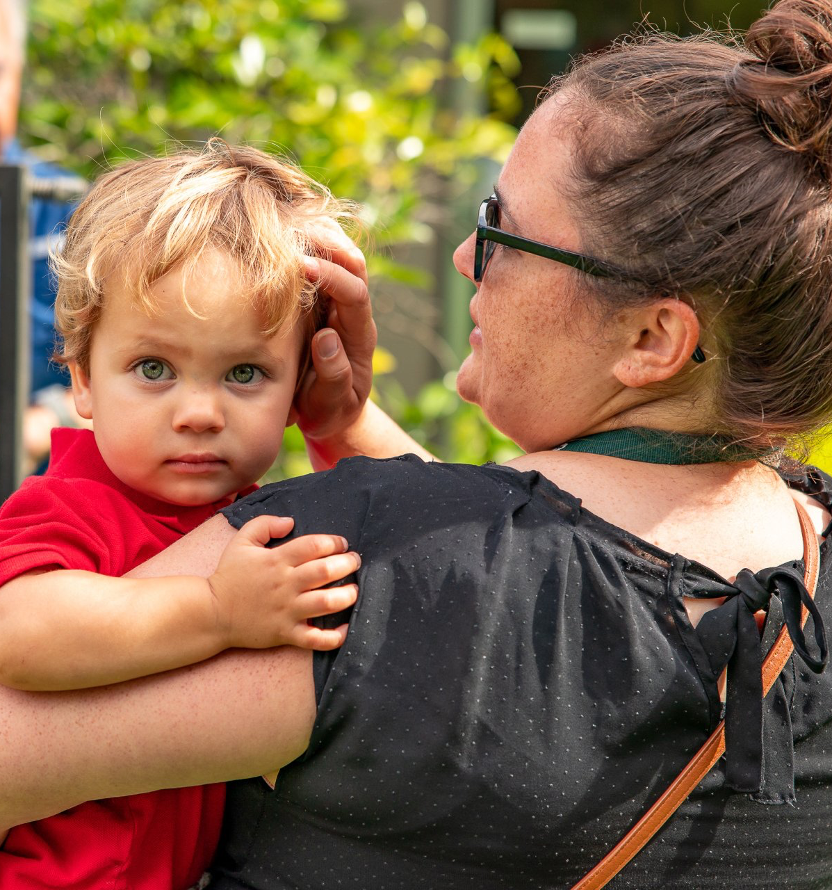 A woman wearing sunglasses is holding a baby in her arms