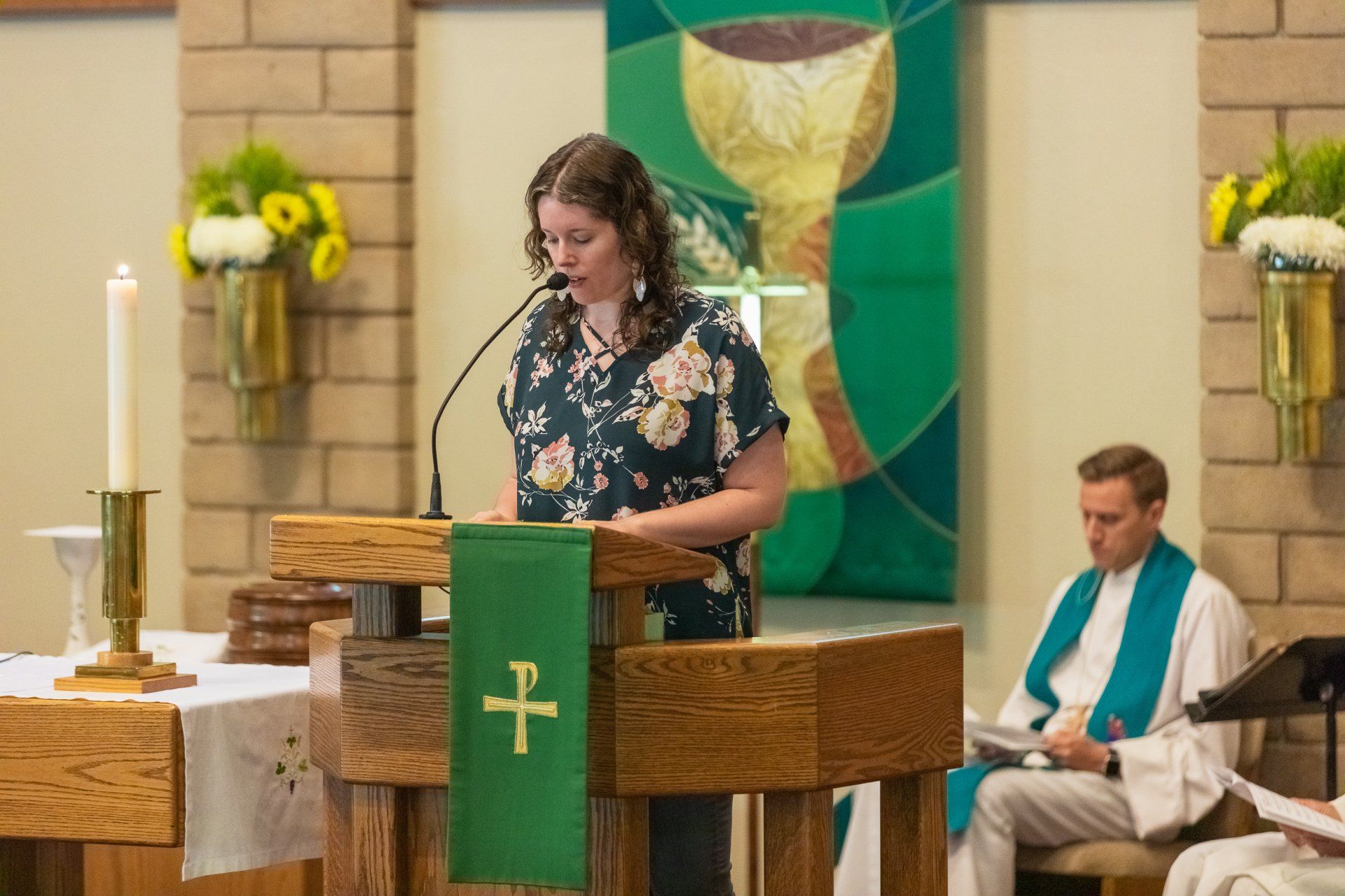 A woman is standing at a podium in front of a microphone in a church.