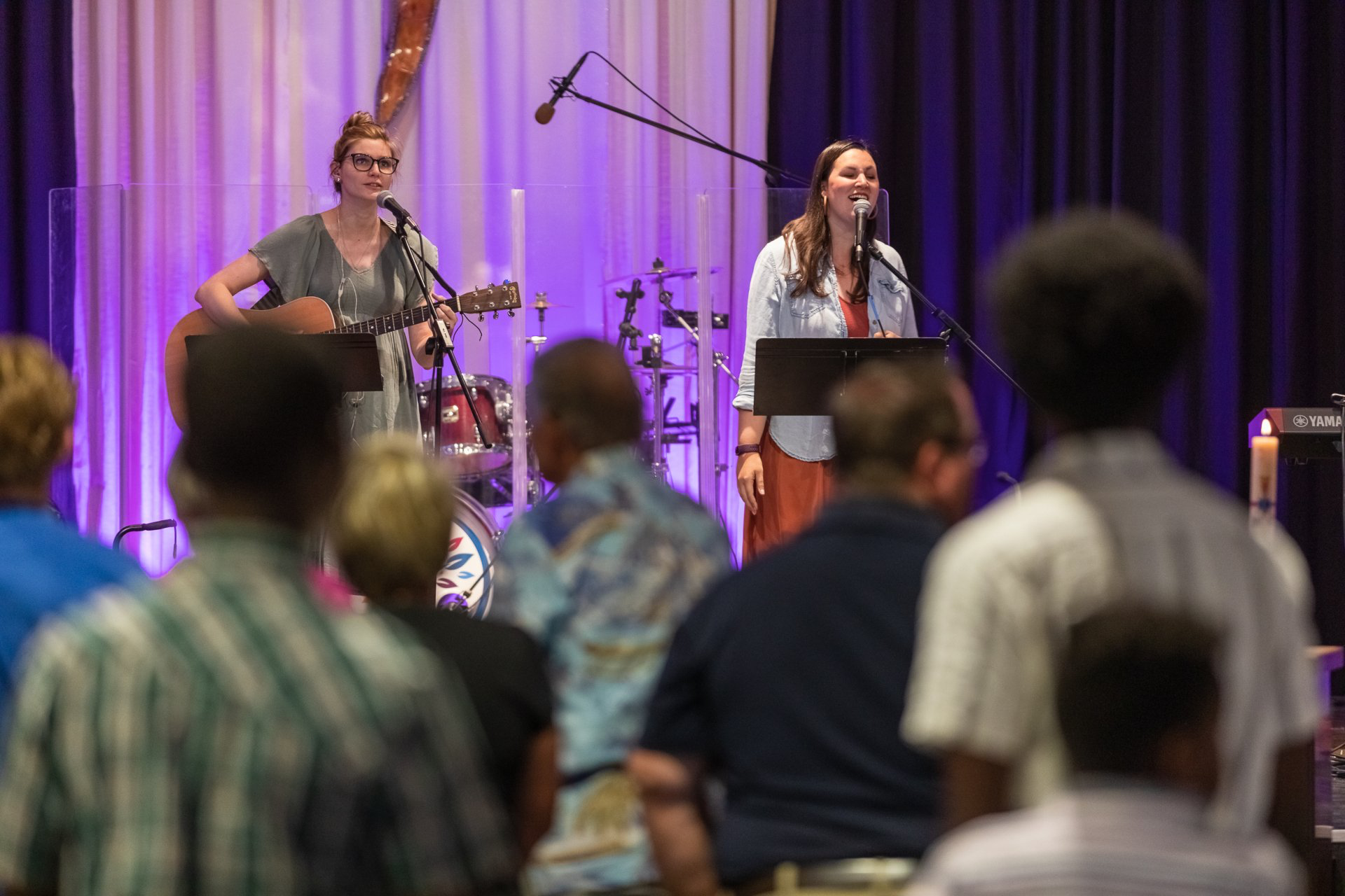 A group of people are sitting in front of a stage watching a band perform.