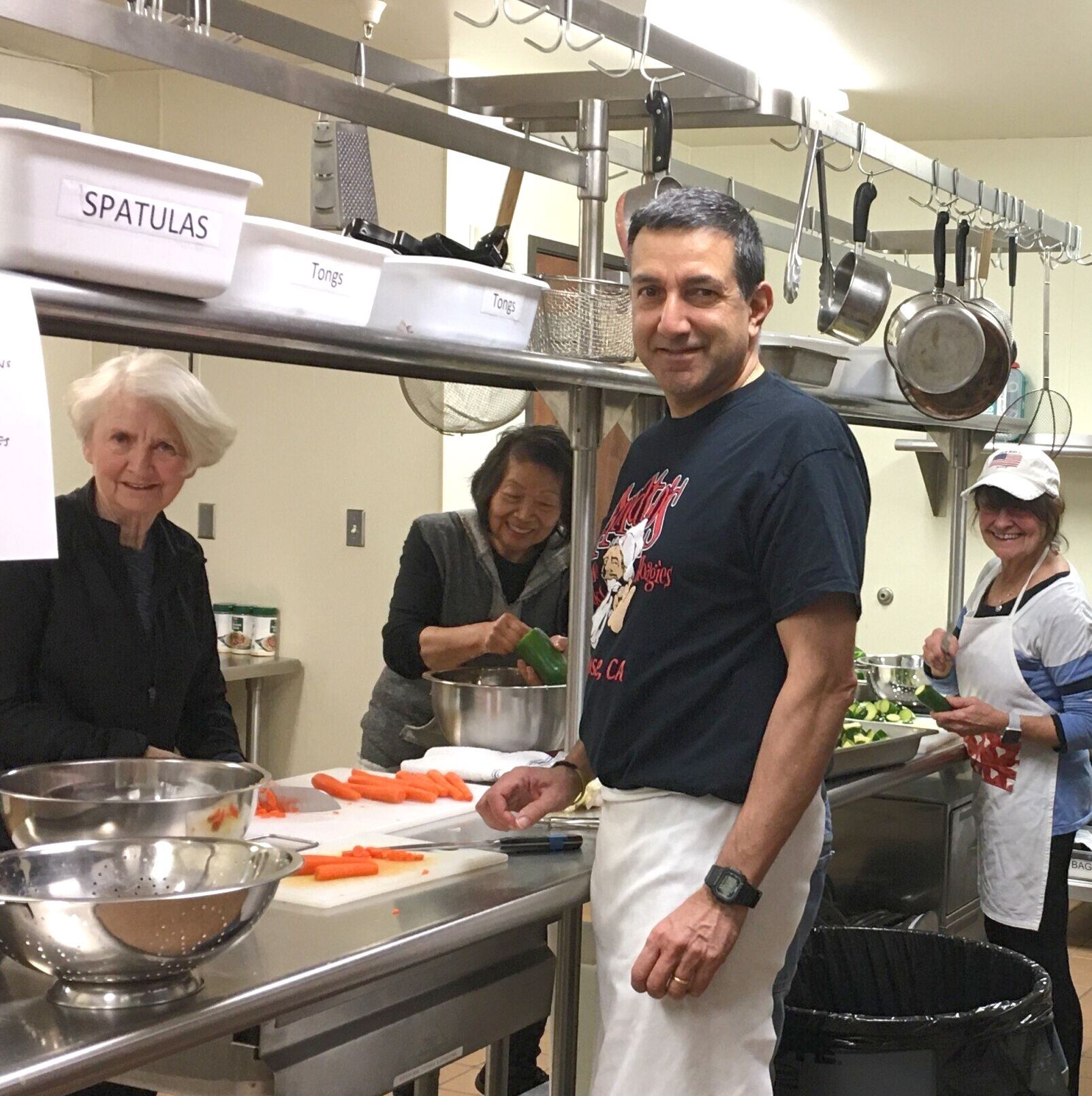 A group of people in a kitchen with a sign that says spatulas