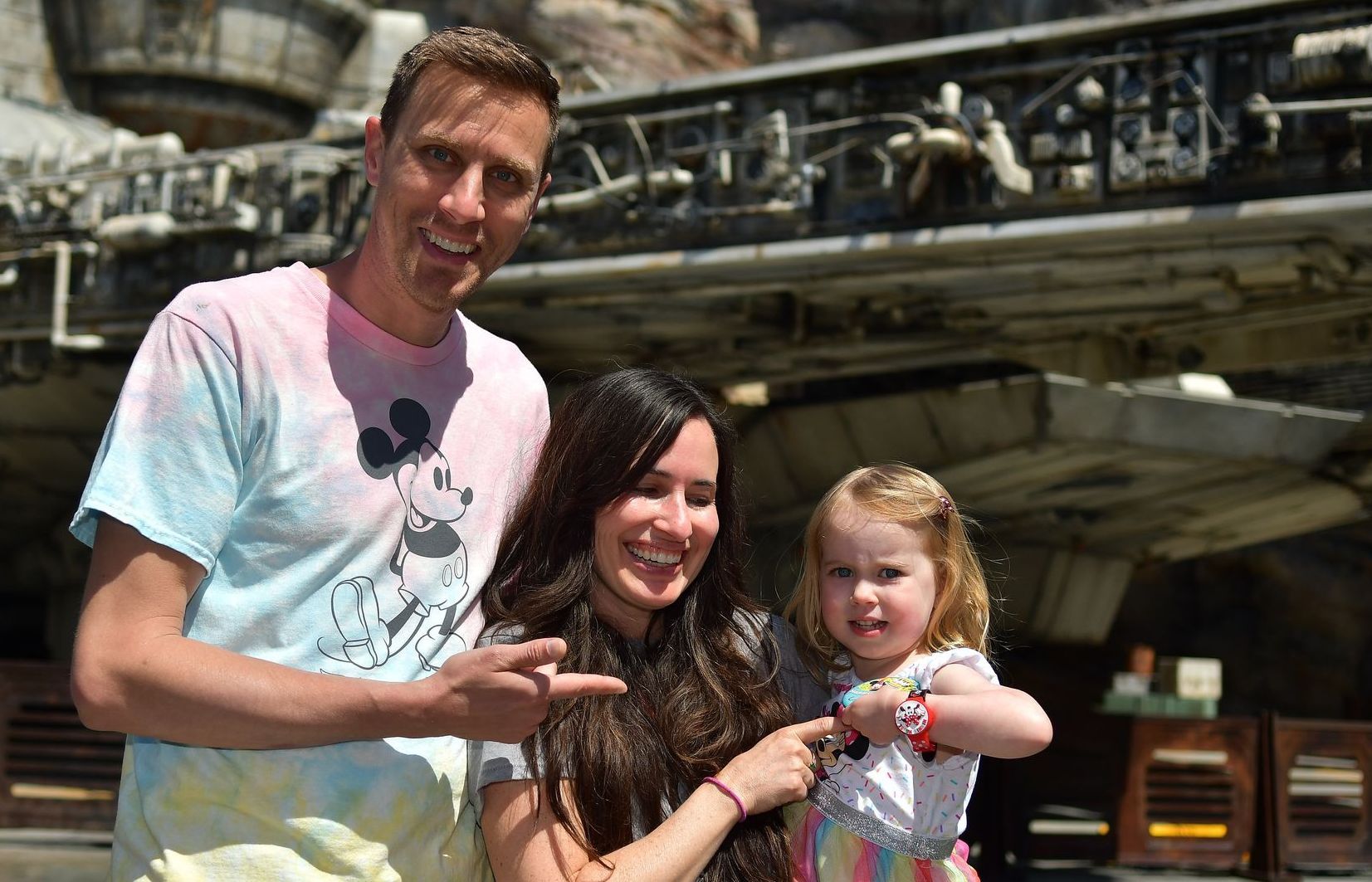 Pastor Ralph, his wife, and daughter are posing for a picture in front of a millennium falcon.
