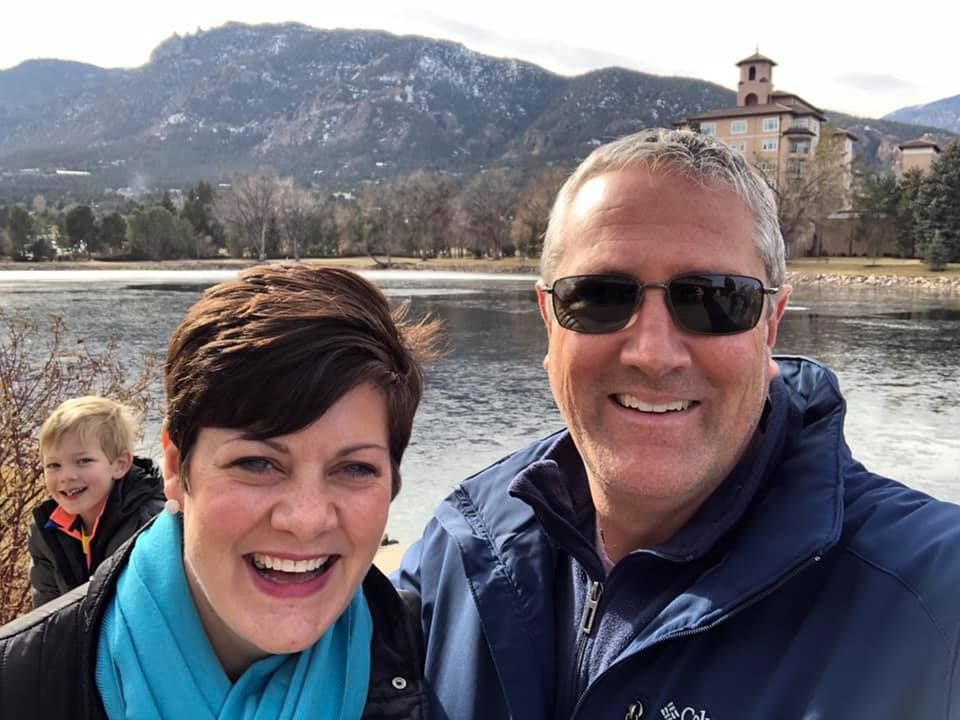 Pastor Derek and his wife posing for a picture in front of a lake.