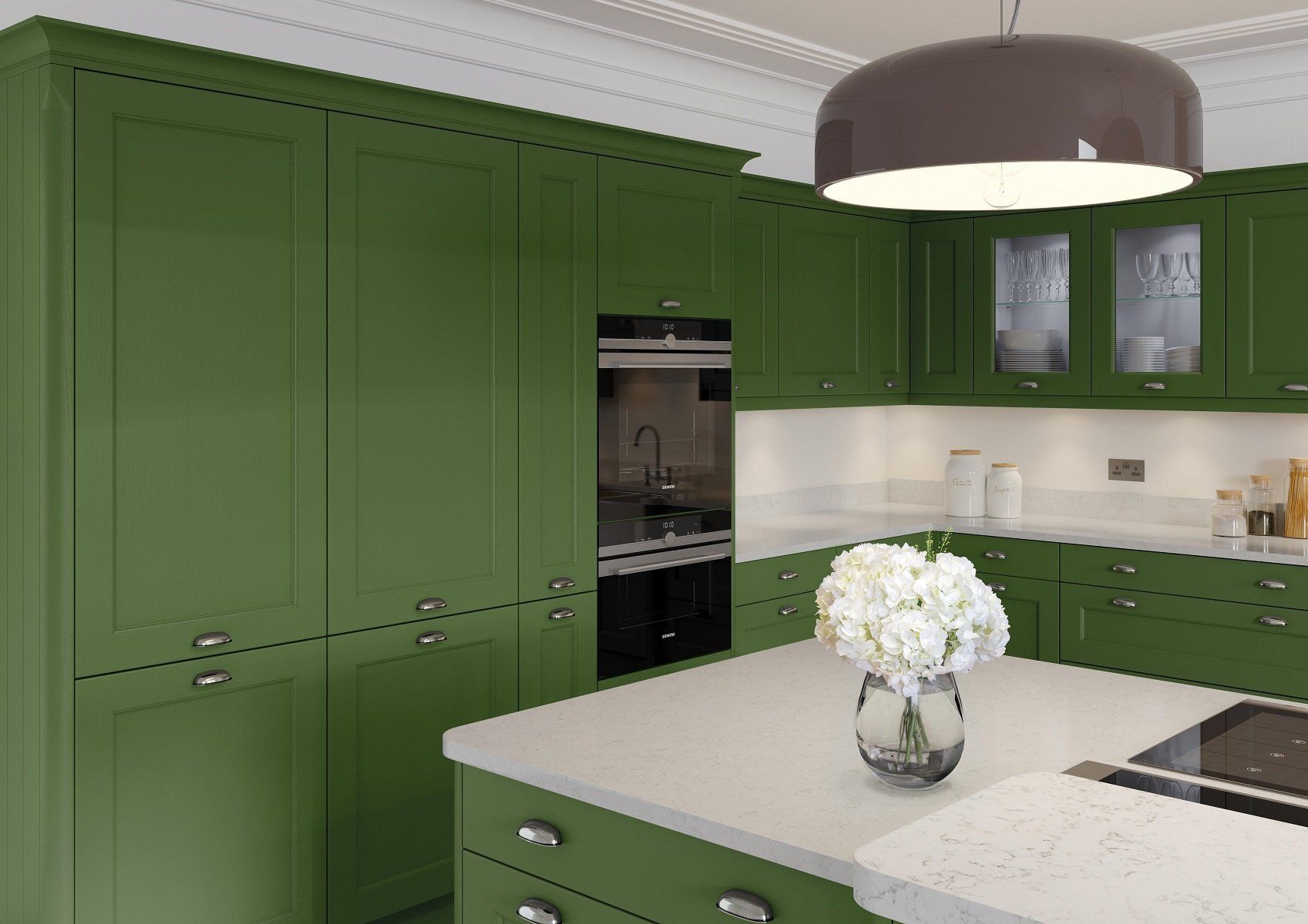 Finsbury Edwardian Green Kitchen Tall fridge freezer units and oven housing with a white quartz and upstands with white flowers in vase
