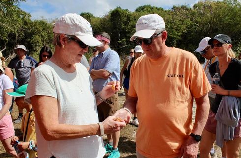 Woman placing something in man's hand; people watching outdoors.