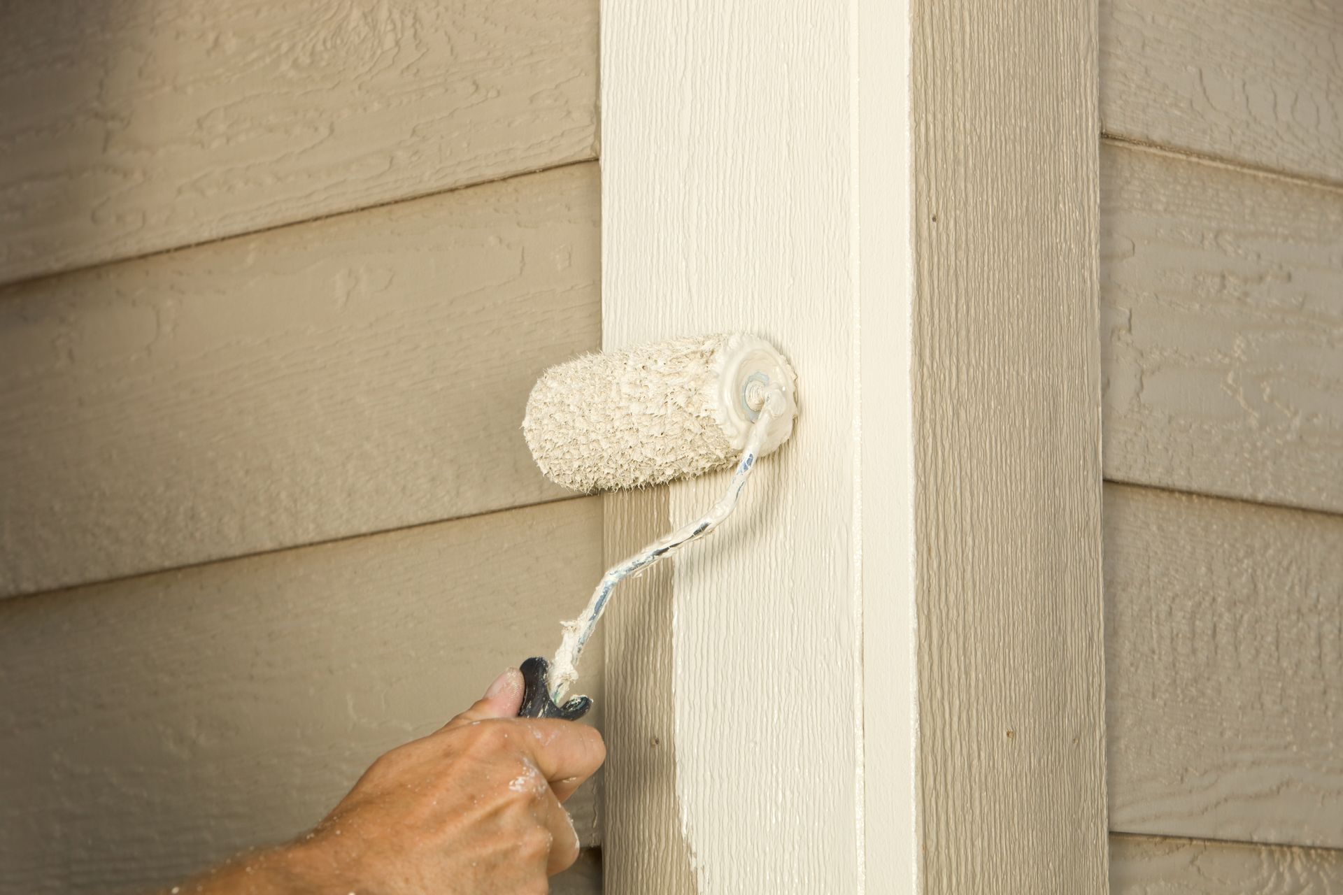 A person is painting a pole with a paint roller.