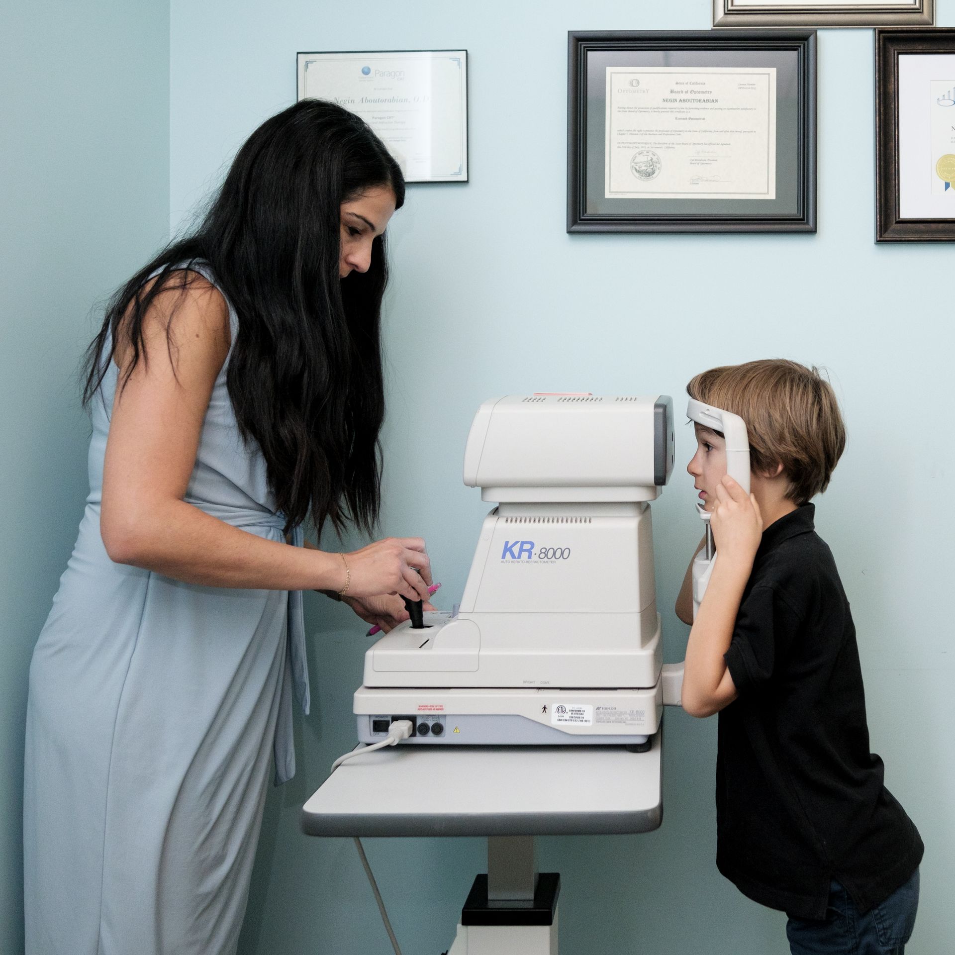 young girl covering one eye to read eye test card