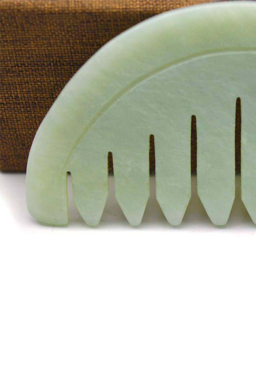 A green comb is sitting on top of a wooden box.