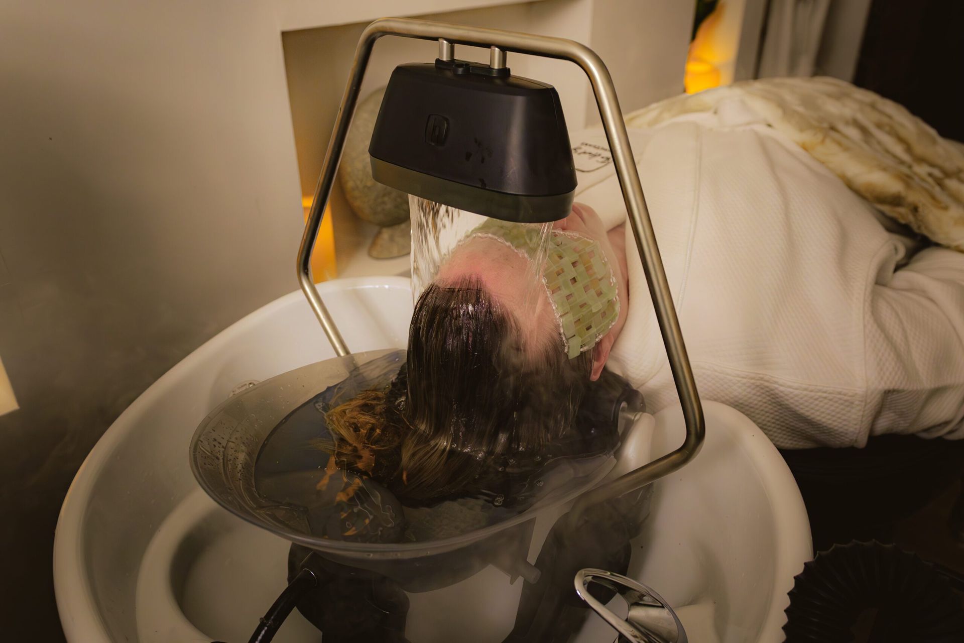 A woman is washing her hair in a sink.