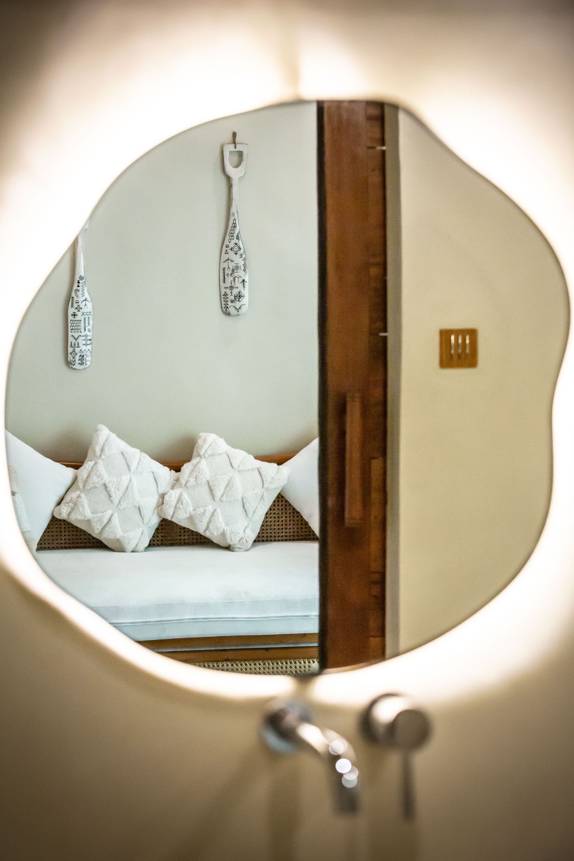 A bathroom mirror with a couch and pillows reflected in it