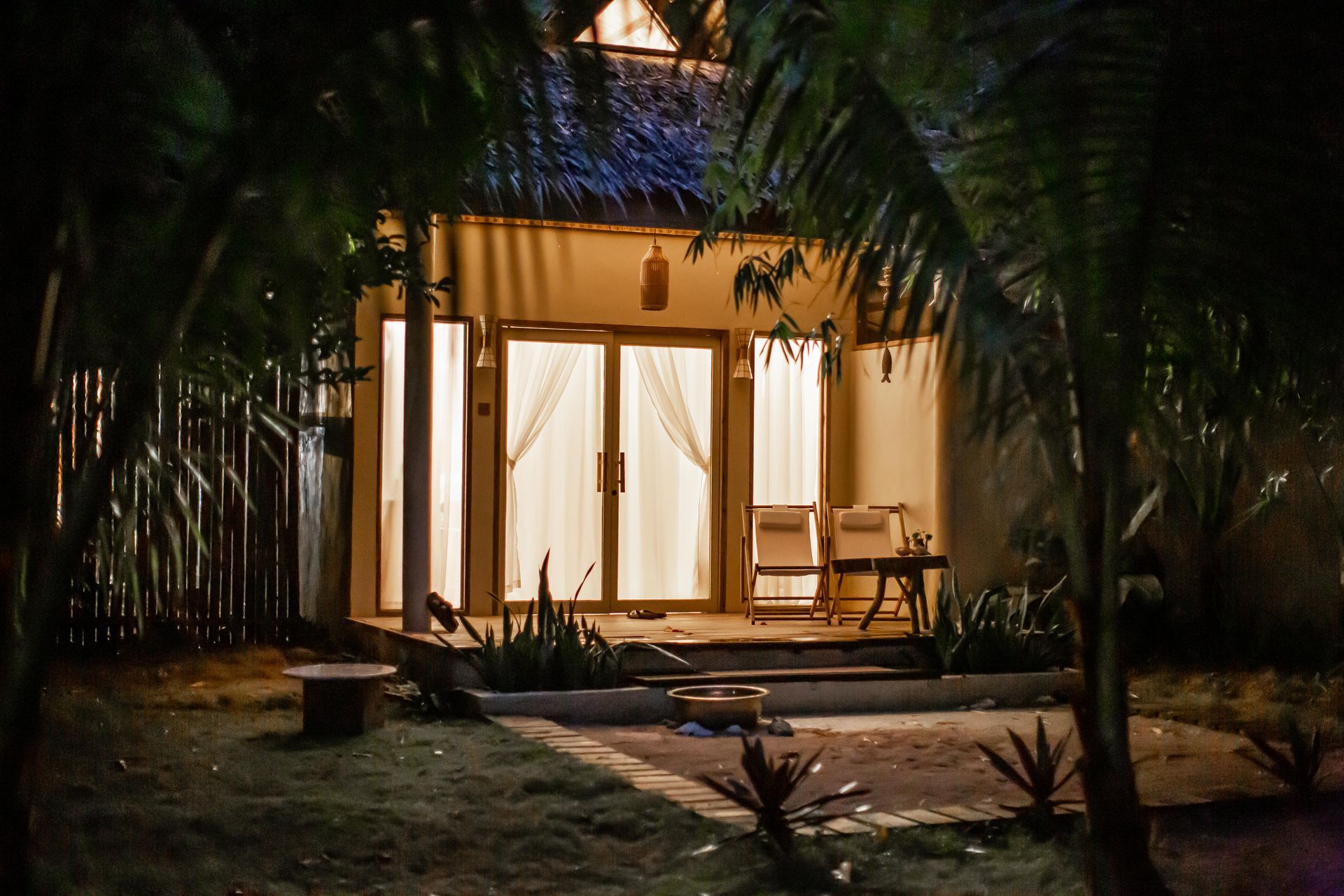 A house is lit up at night in the middle of a forest.
