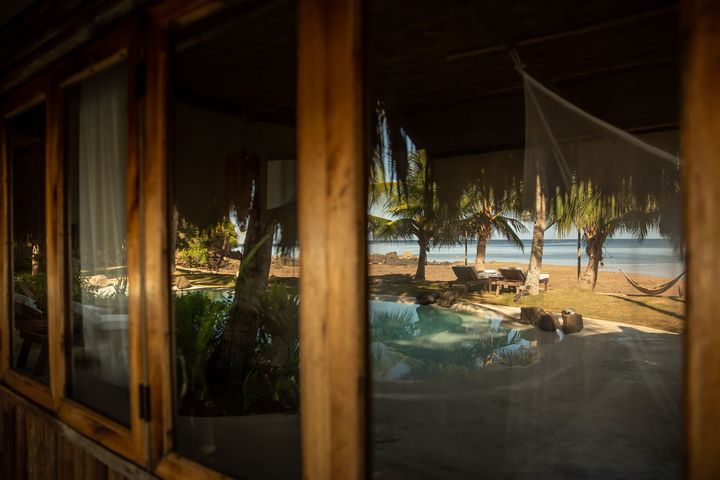 A view of a swimming pool and a beach from a window.