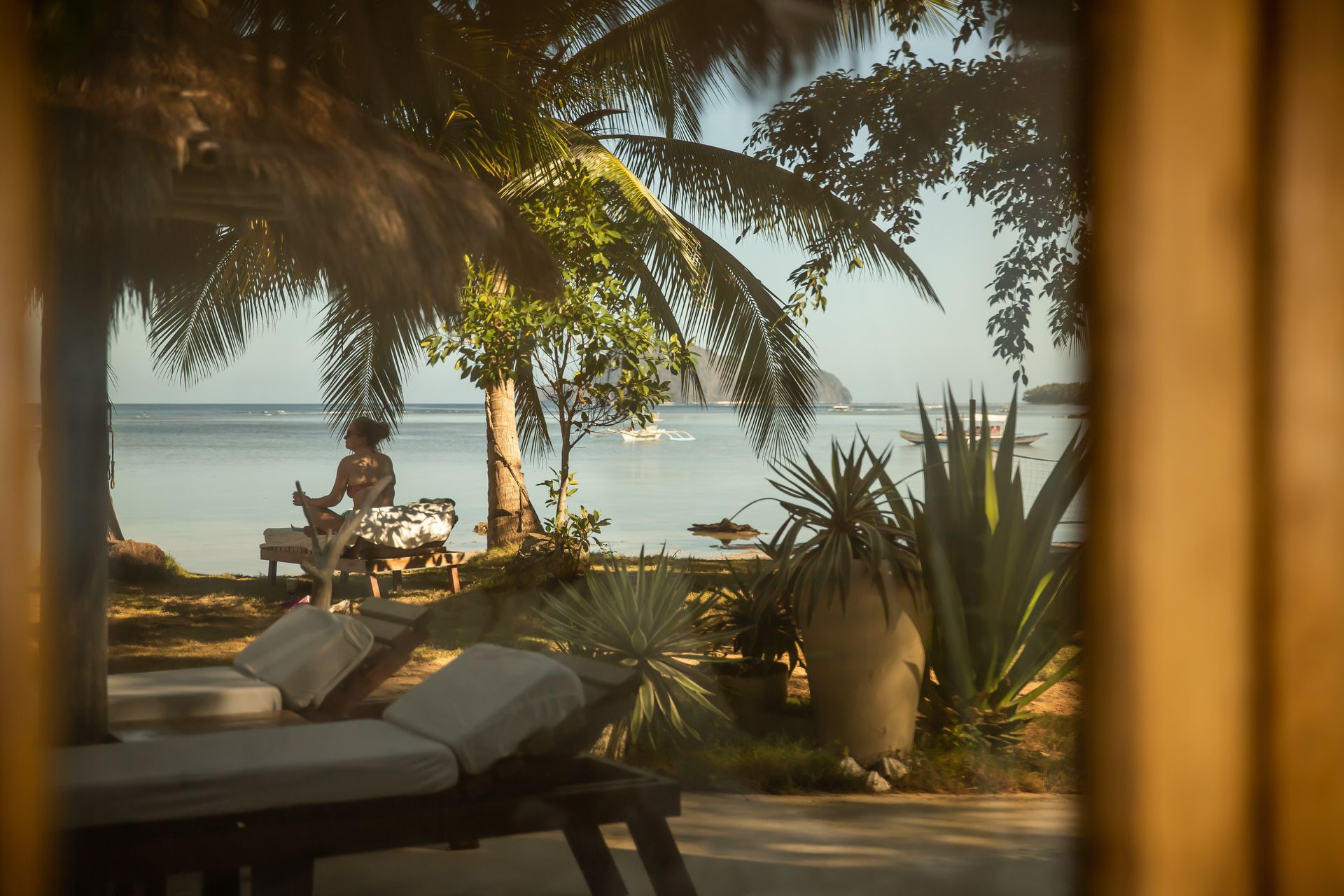 A woman is sitting on a lounge chair near the ocean.