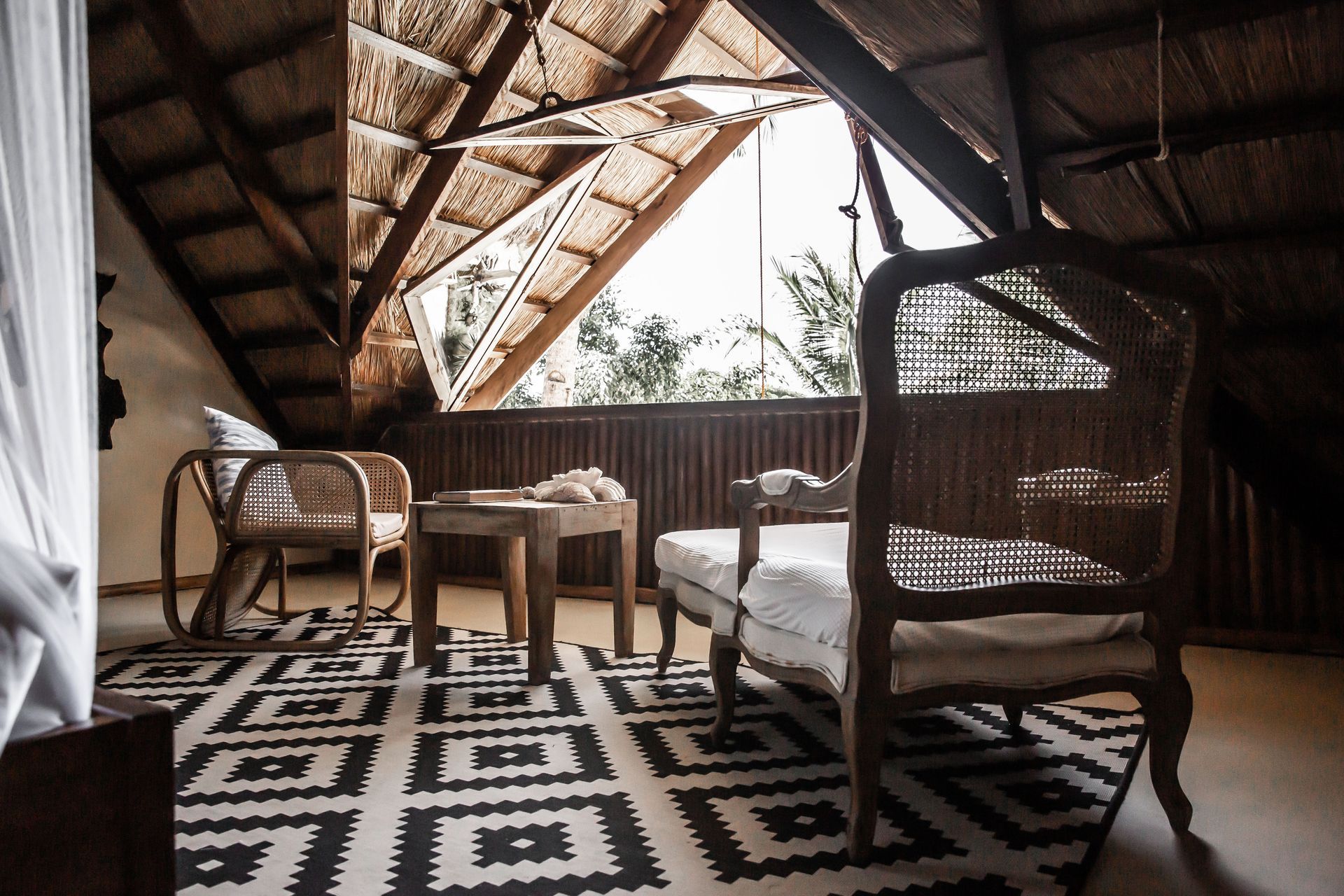 A living room with a thatched roof and a rug