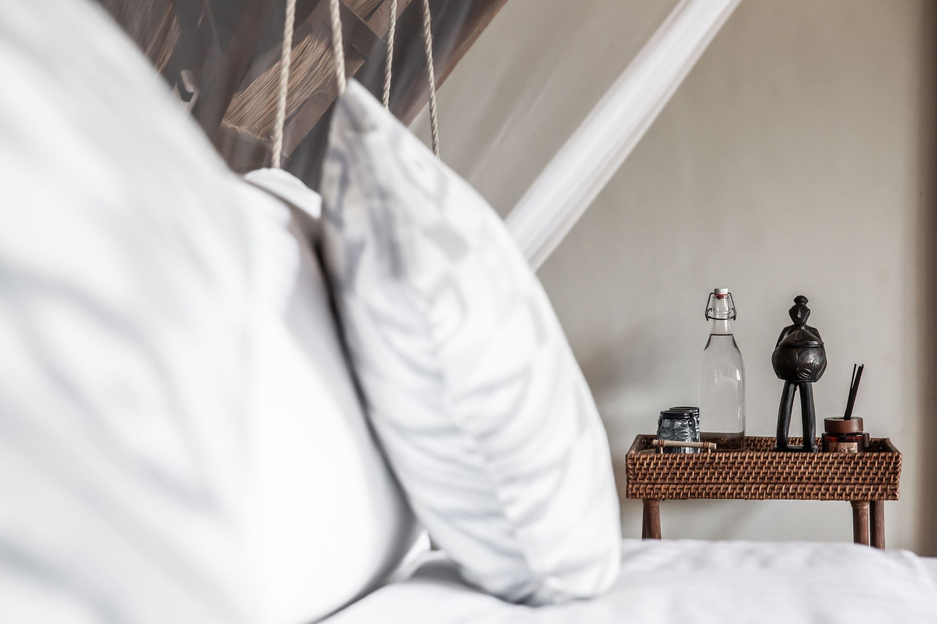 A bed with white sheets and a table with a bottle on it