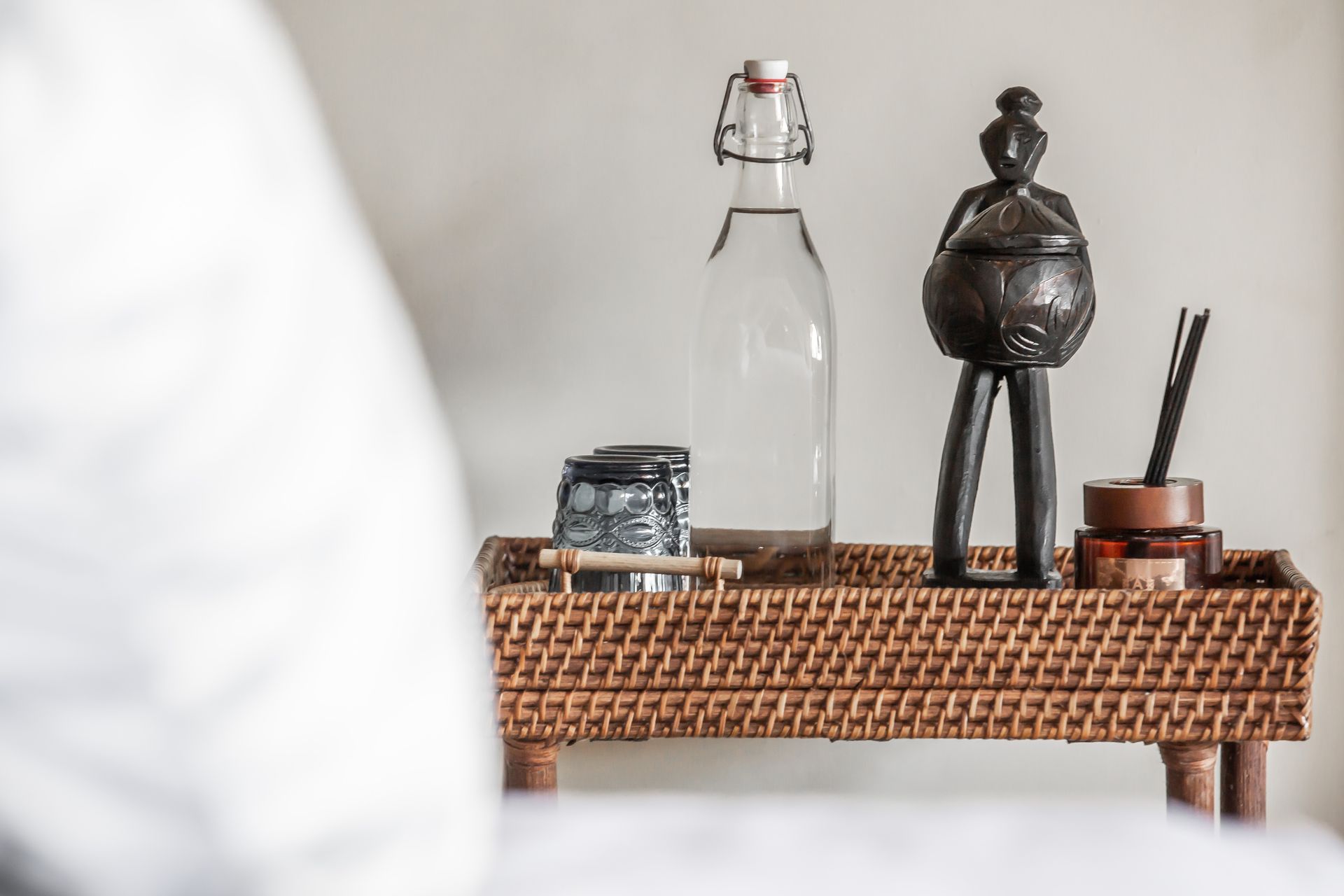 A wicker tray with a bottle of water and a statue on it.