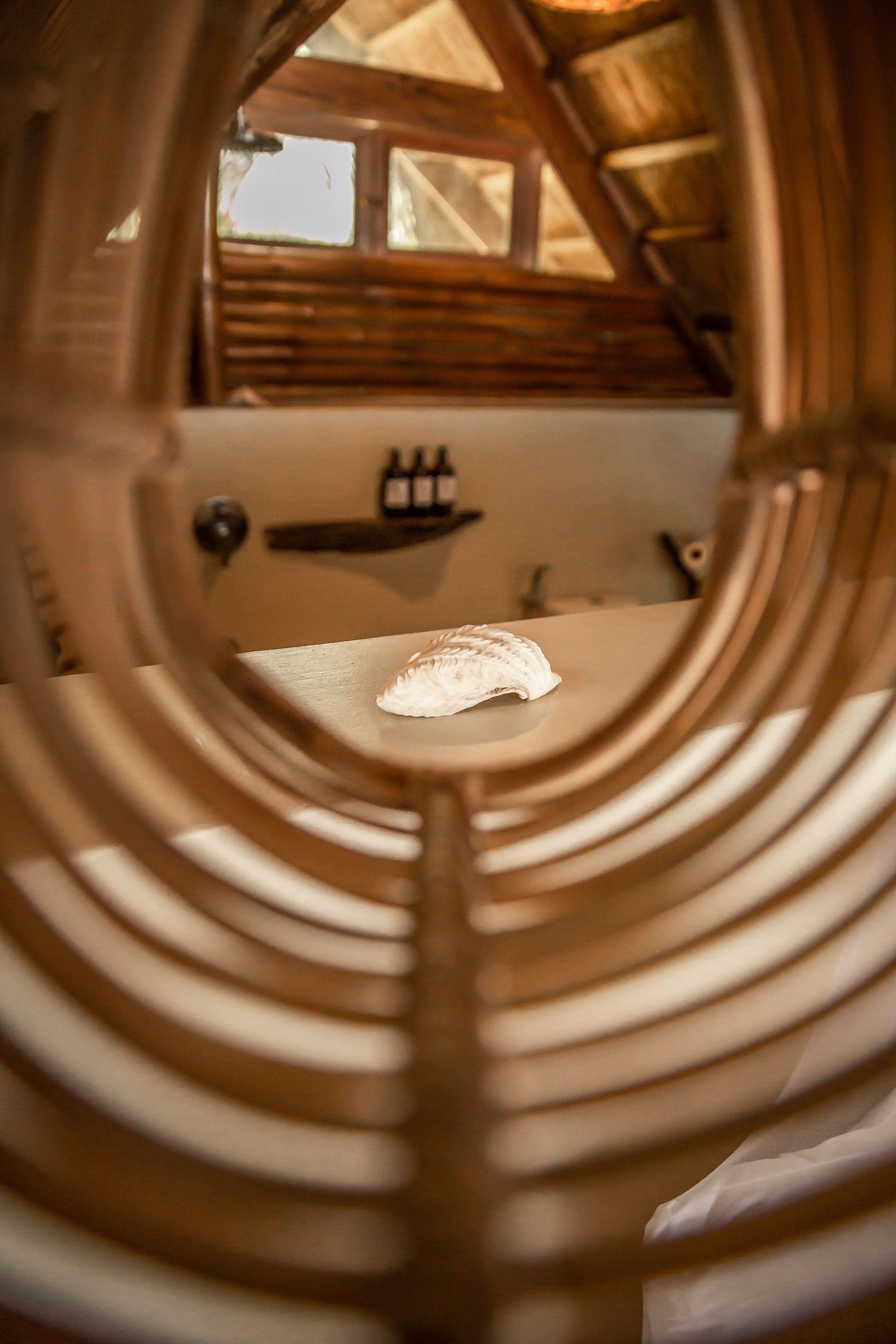 A close up of a wooden chair with a bed in the background