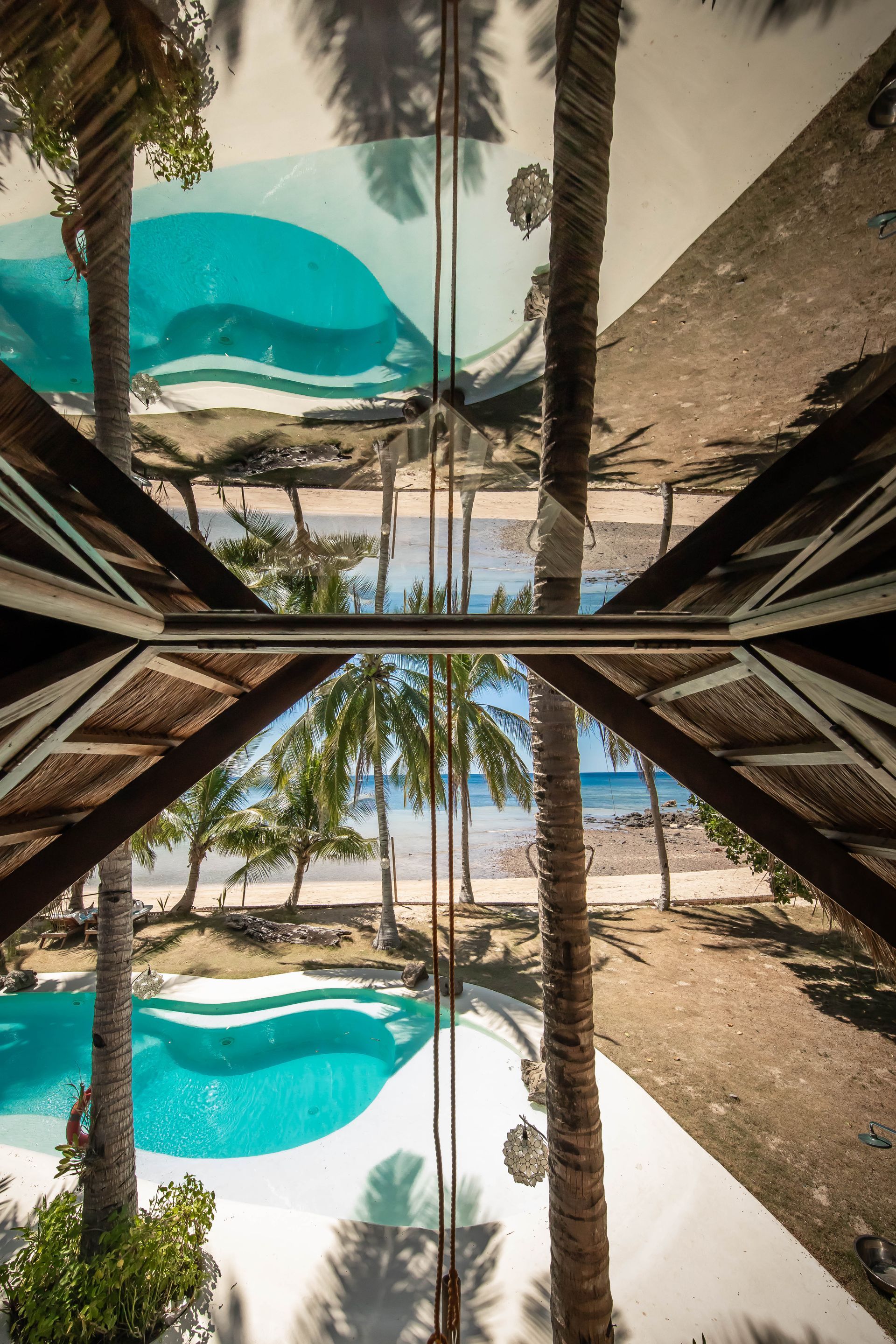 A reflection of palm trees and a swimming pool in a mirror.