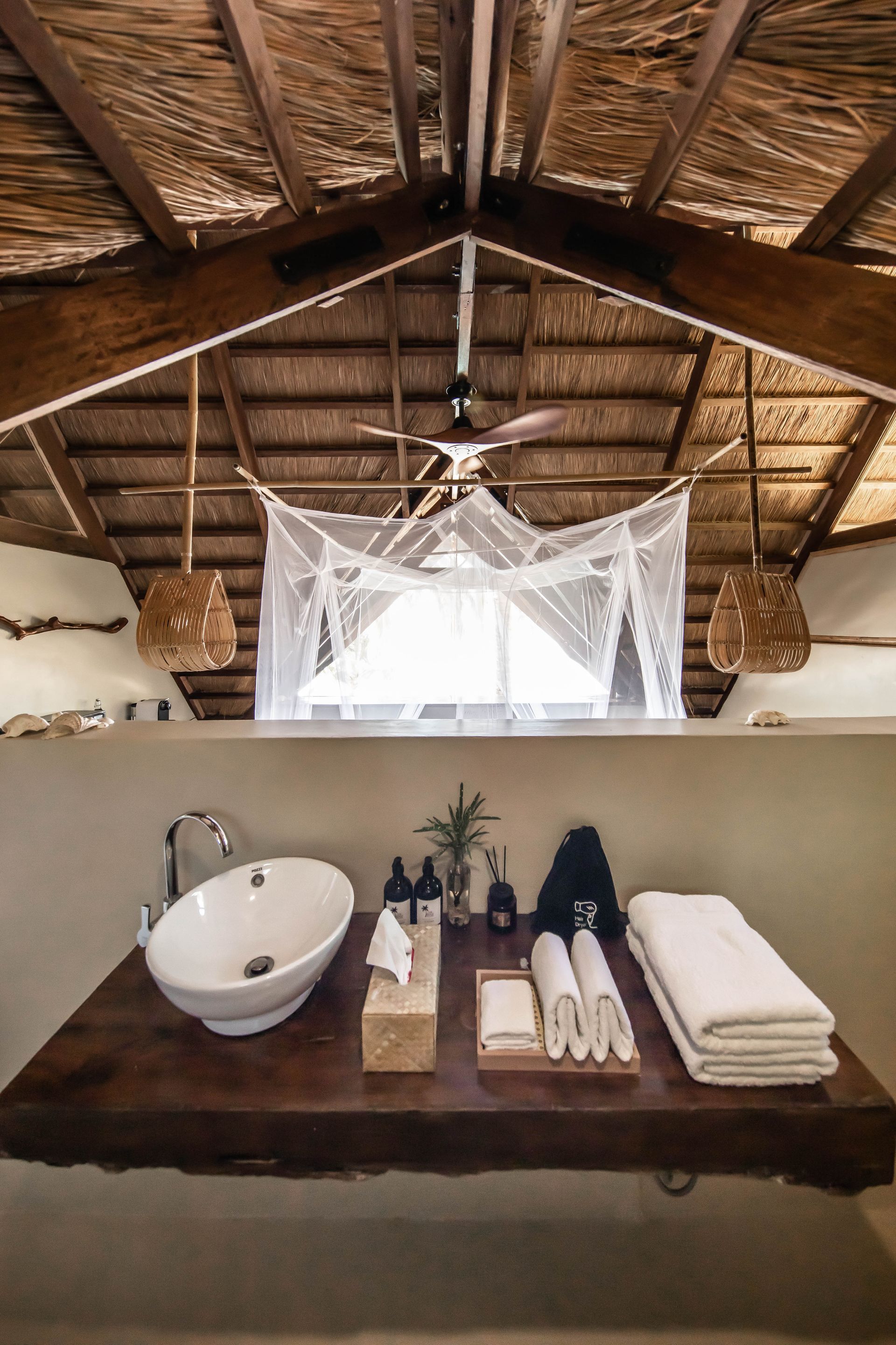 A bathroom with a sink , towels and a ceiling fan.