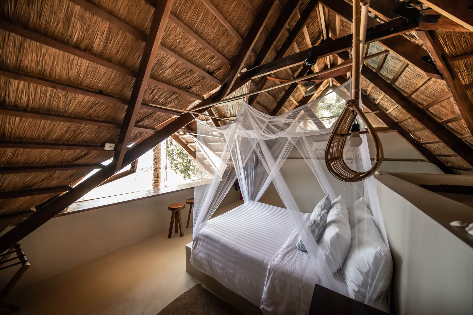 A bedroom with a canopy bed and a thatched roof.