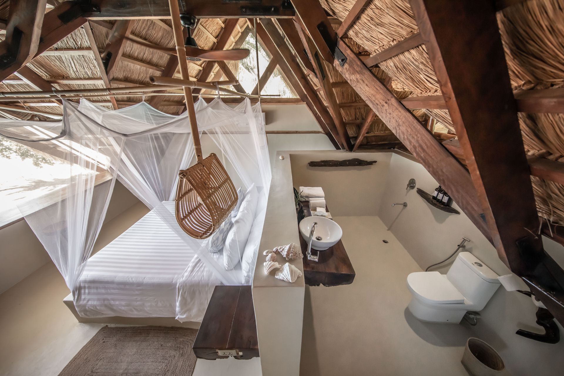 A bathroom with a toilet , sink , and canopy bed.
