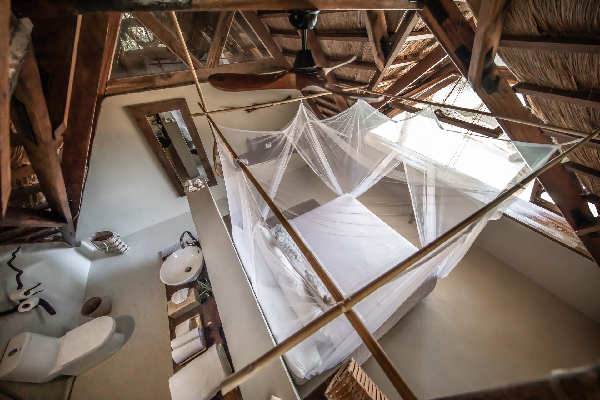 A bedroom with a mosquito net and a ceiling fan
