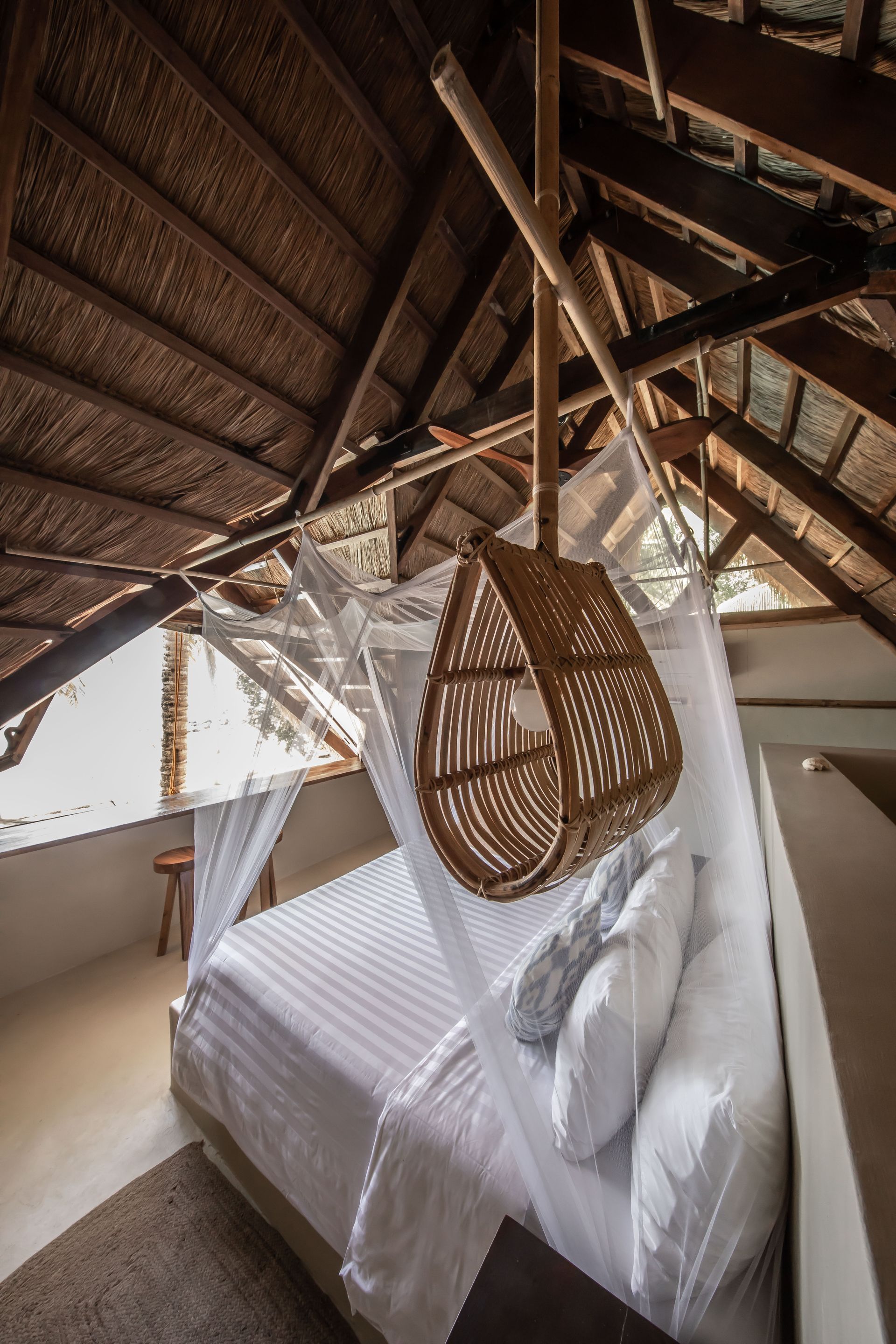 A bedroom with a bed and a hammock hanging from the ceiling.