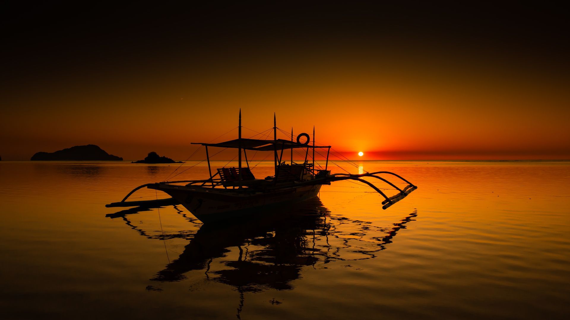 A boat is floating on top of a body of water at sunset.