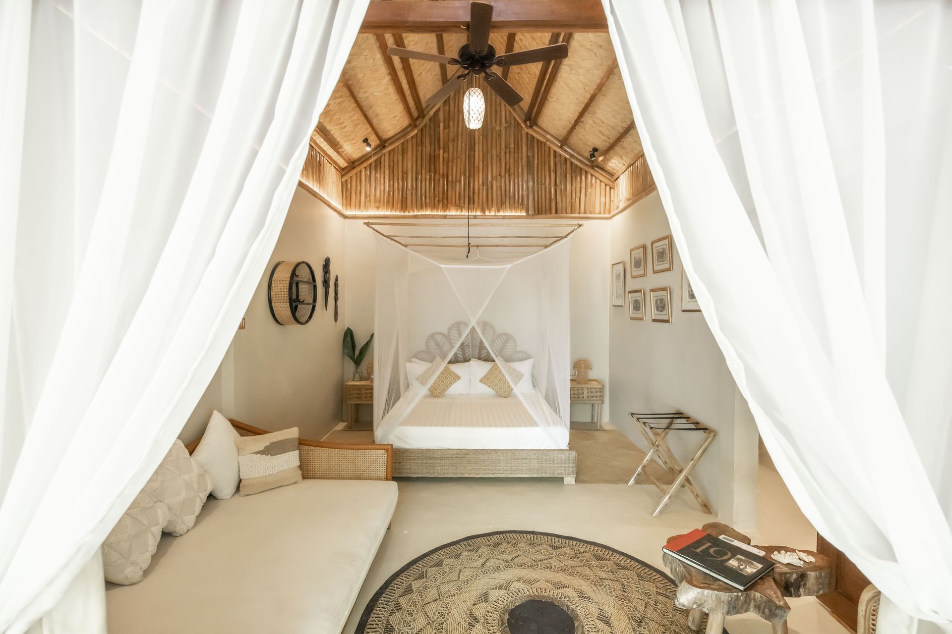 A bedroom with a canopy bed , a couch , a rug and a ceiling fan.