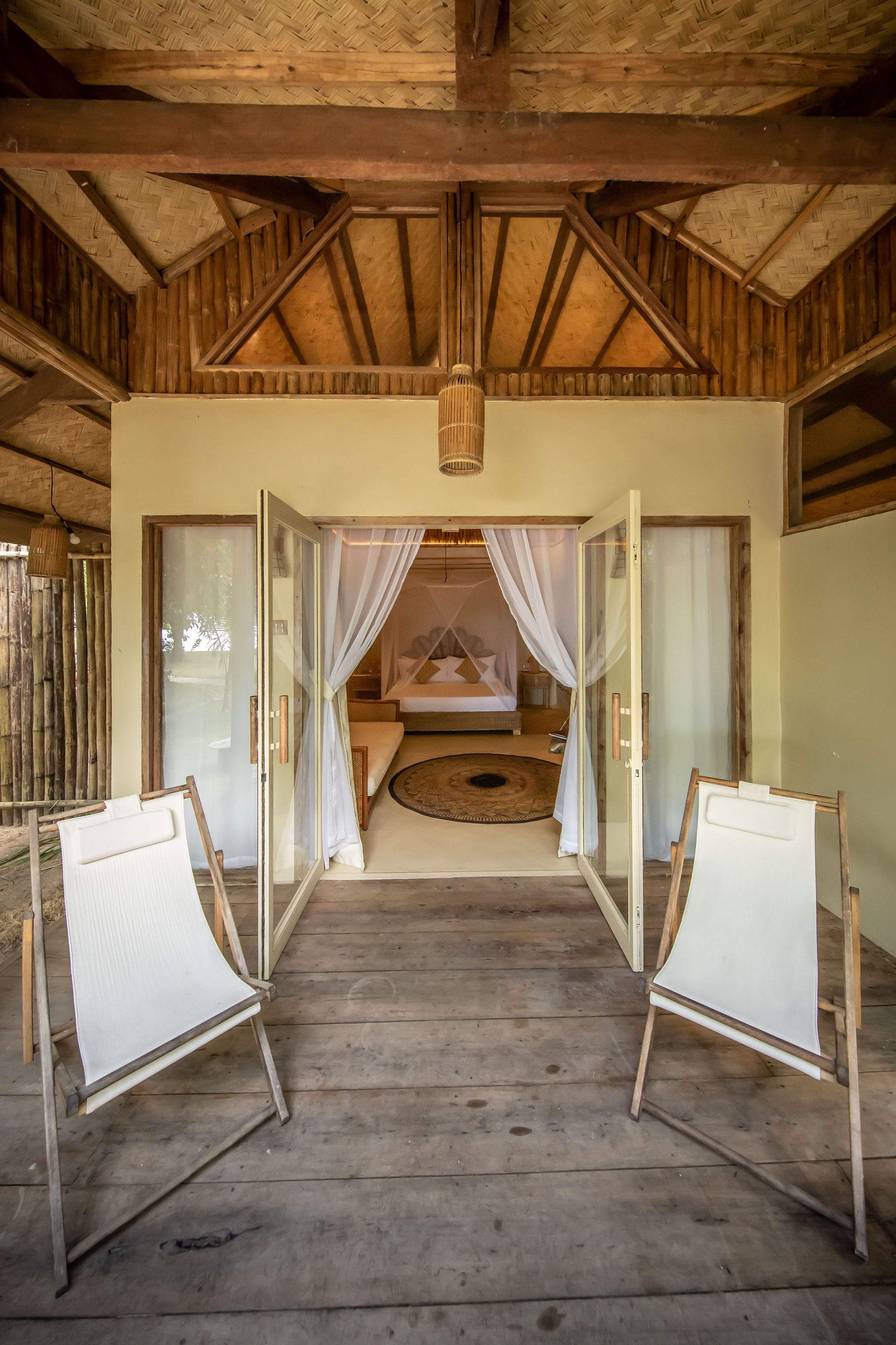 There are two chairs in front of a bedroom with a canopy bed.