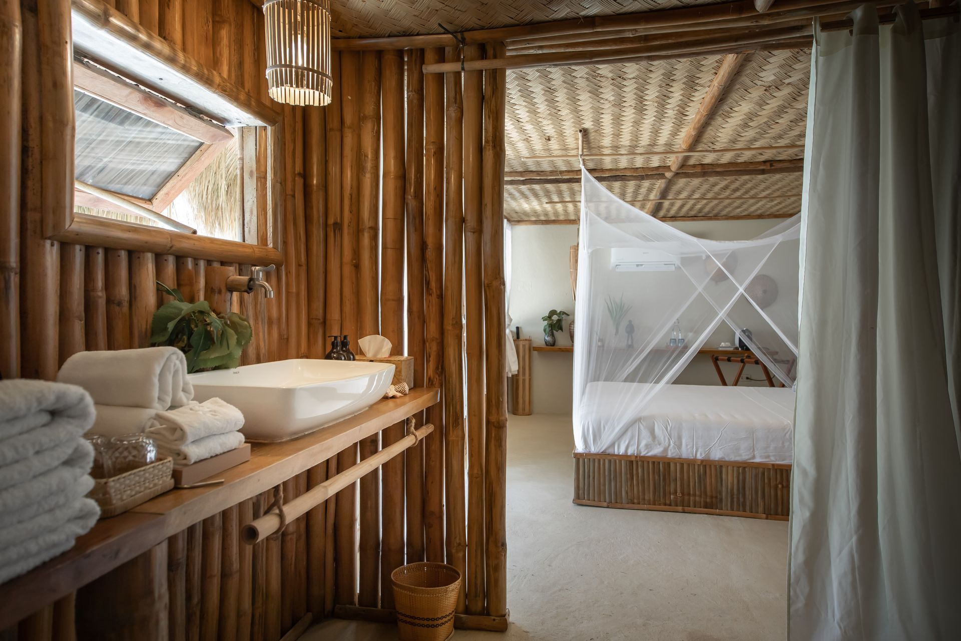 A bathroom with a sink and a bed in the background.