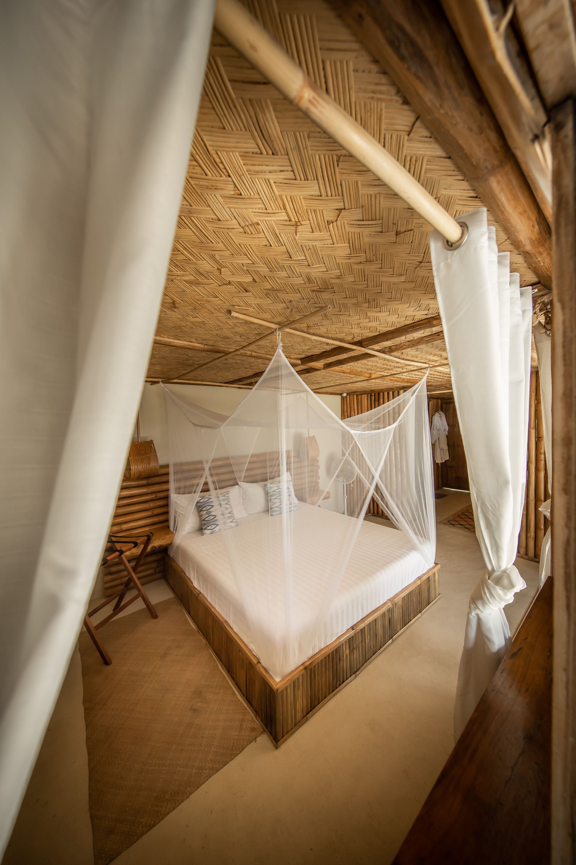 A bedroom with a canopy bed and white curtains.