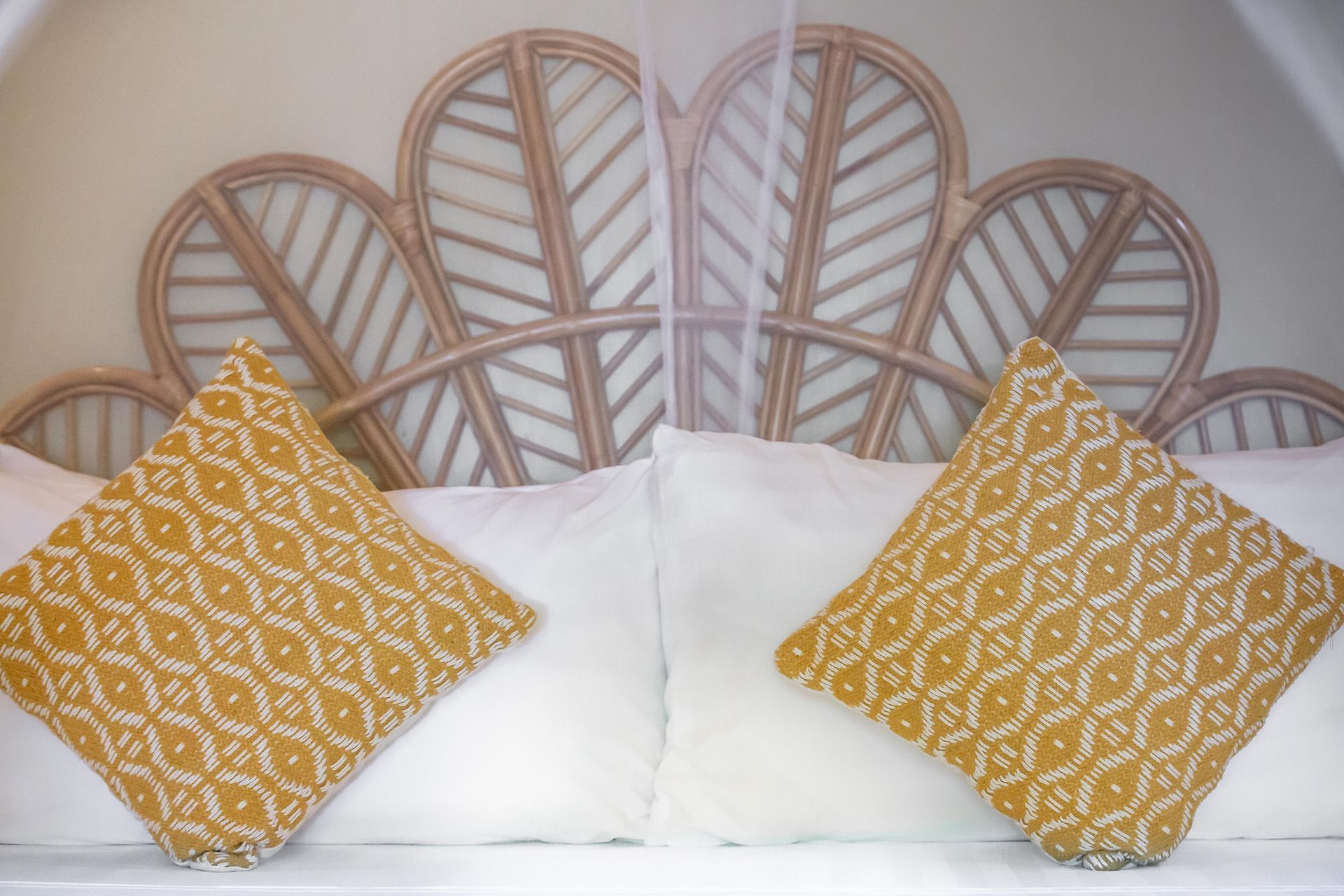 A bed with a wicker headboard and yellow pillows on it.
