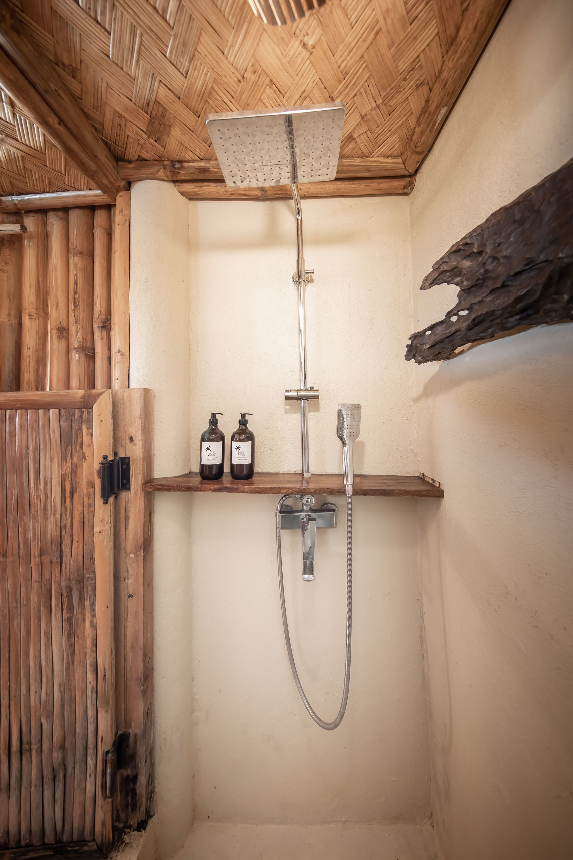 A bathroom with a shower and two bottles of soap on a shelf.