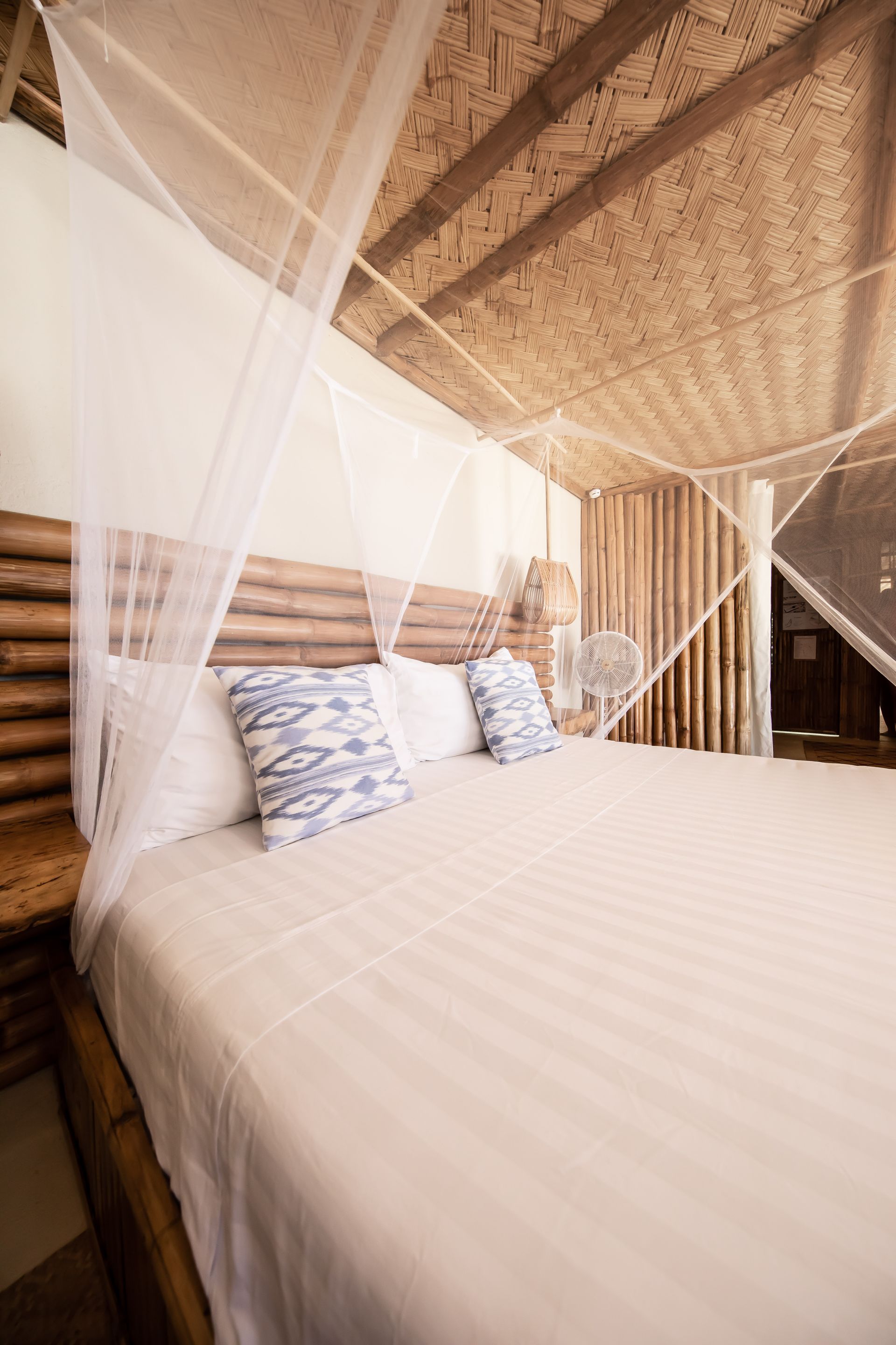A bedroom with a canopy bed and a fan.