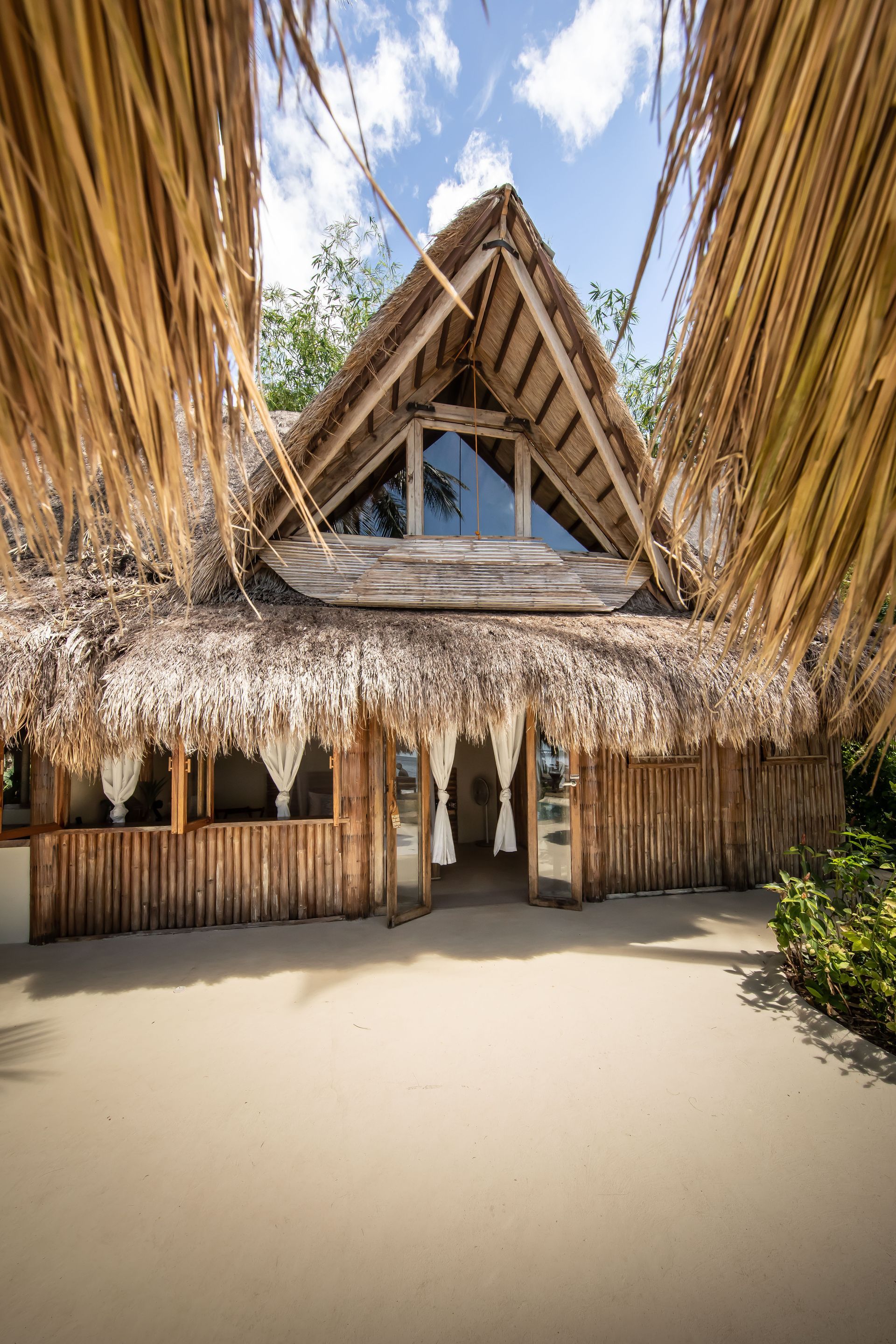 A wooden hut with a thatched roof and a large window.