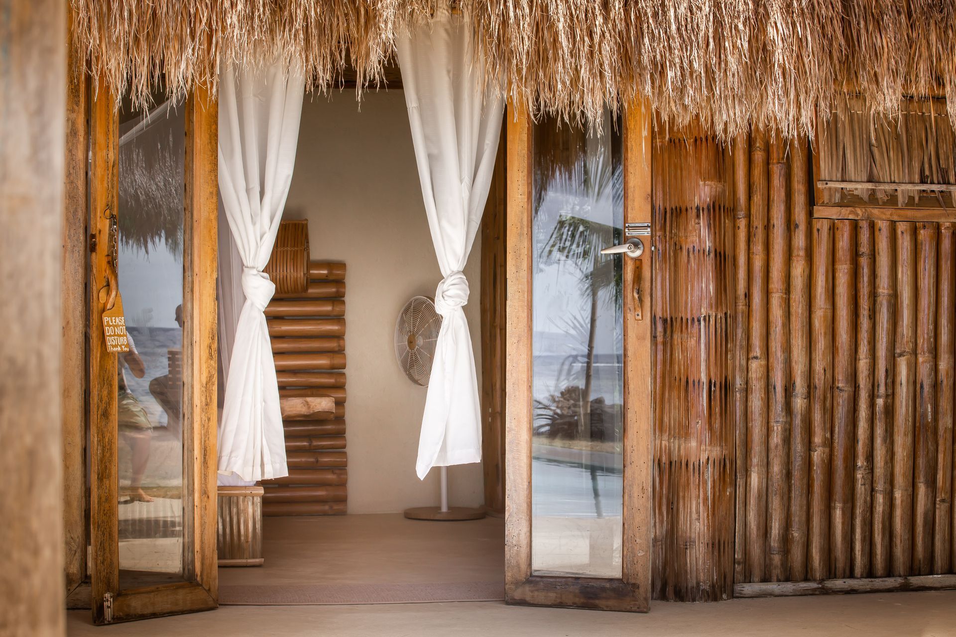 A wooden building with a thatched roof and sliding glass doors.