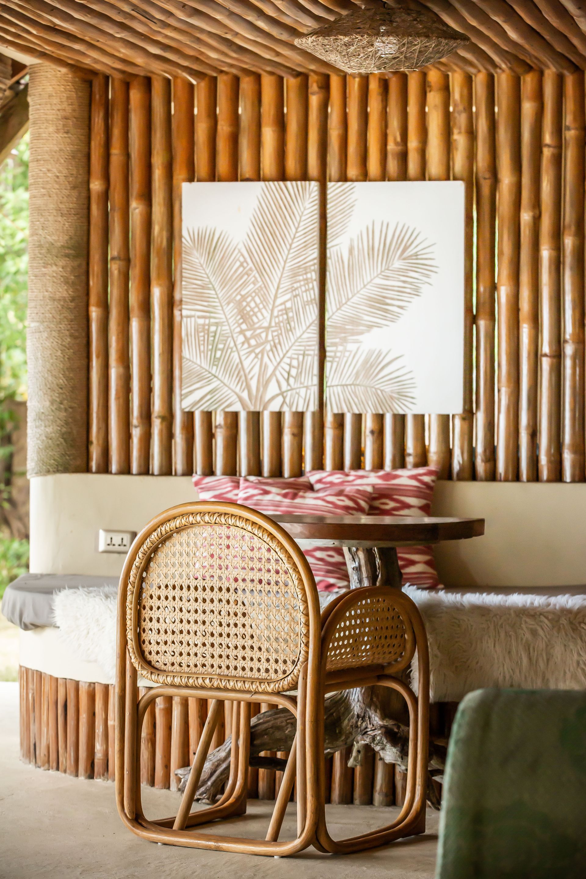 There is a table and chairs in the room with a bamboo wall.