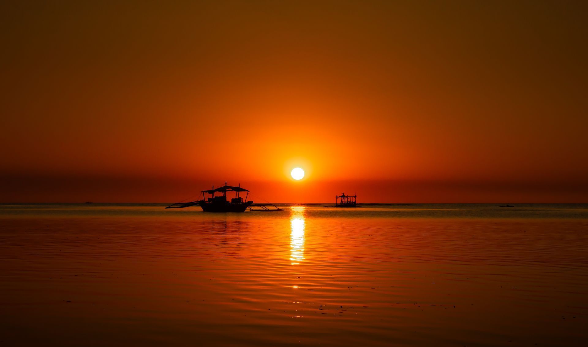 A boat is floating on top of a body of water at sunset.