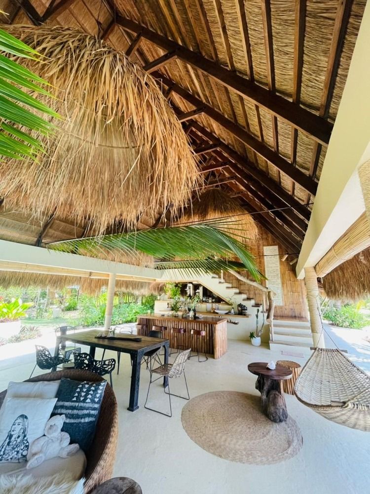 A large room with a thatched roof and a table and chairs