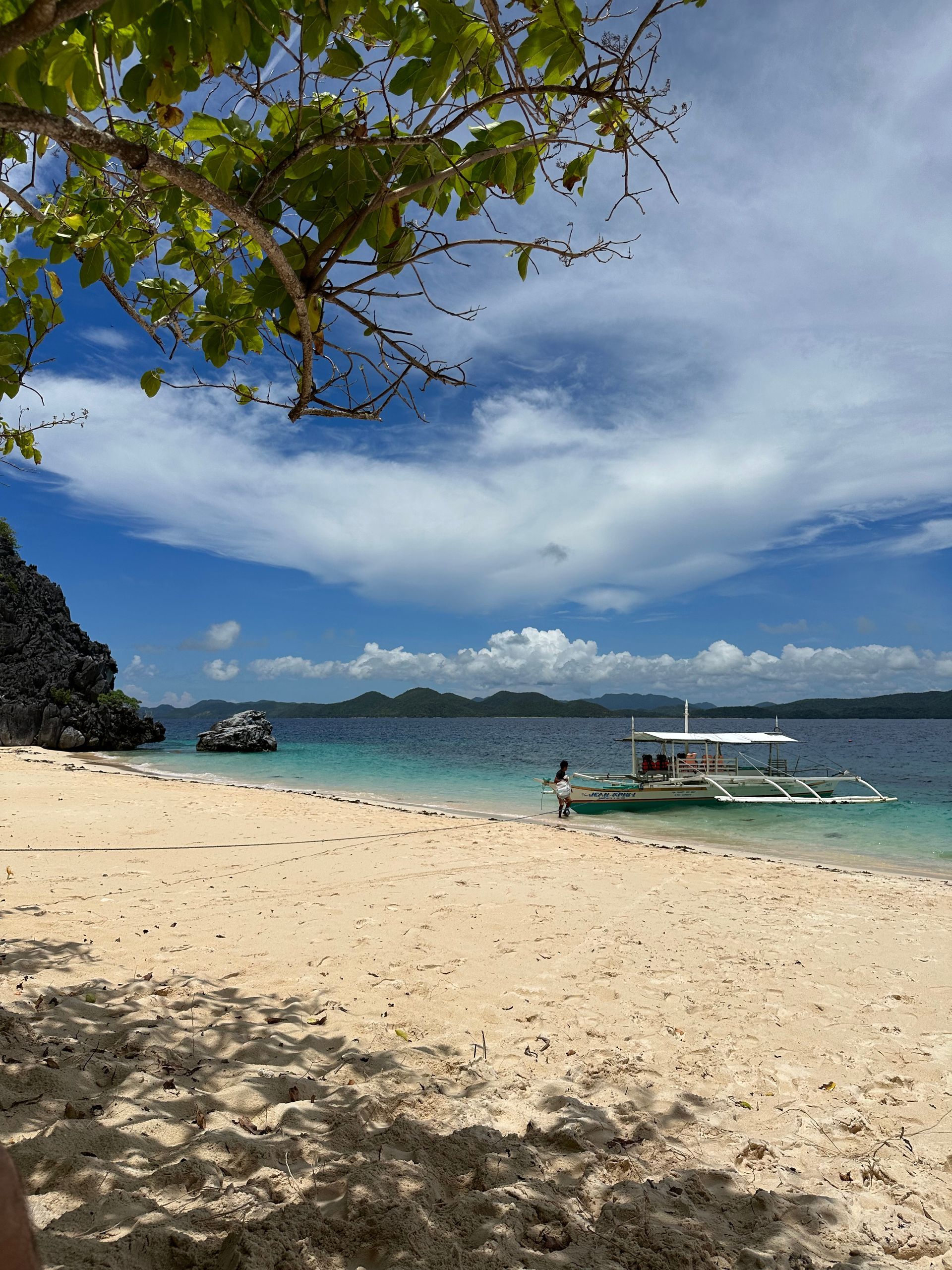 A boat is docked on a sandy beach next to a body of water.