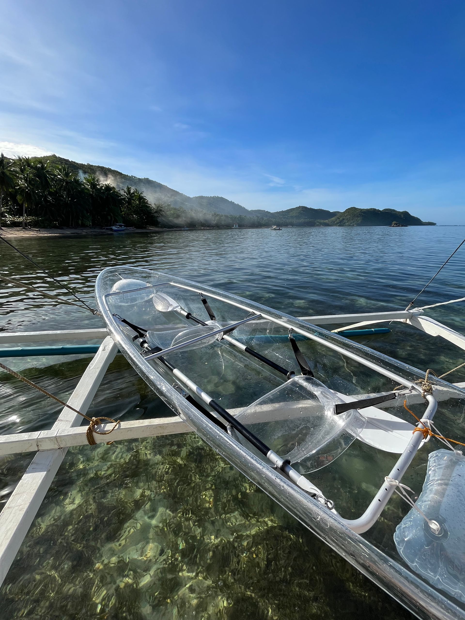 A clear kayak is floating on top of a body of water.