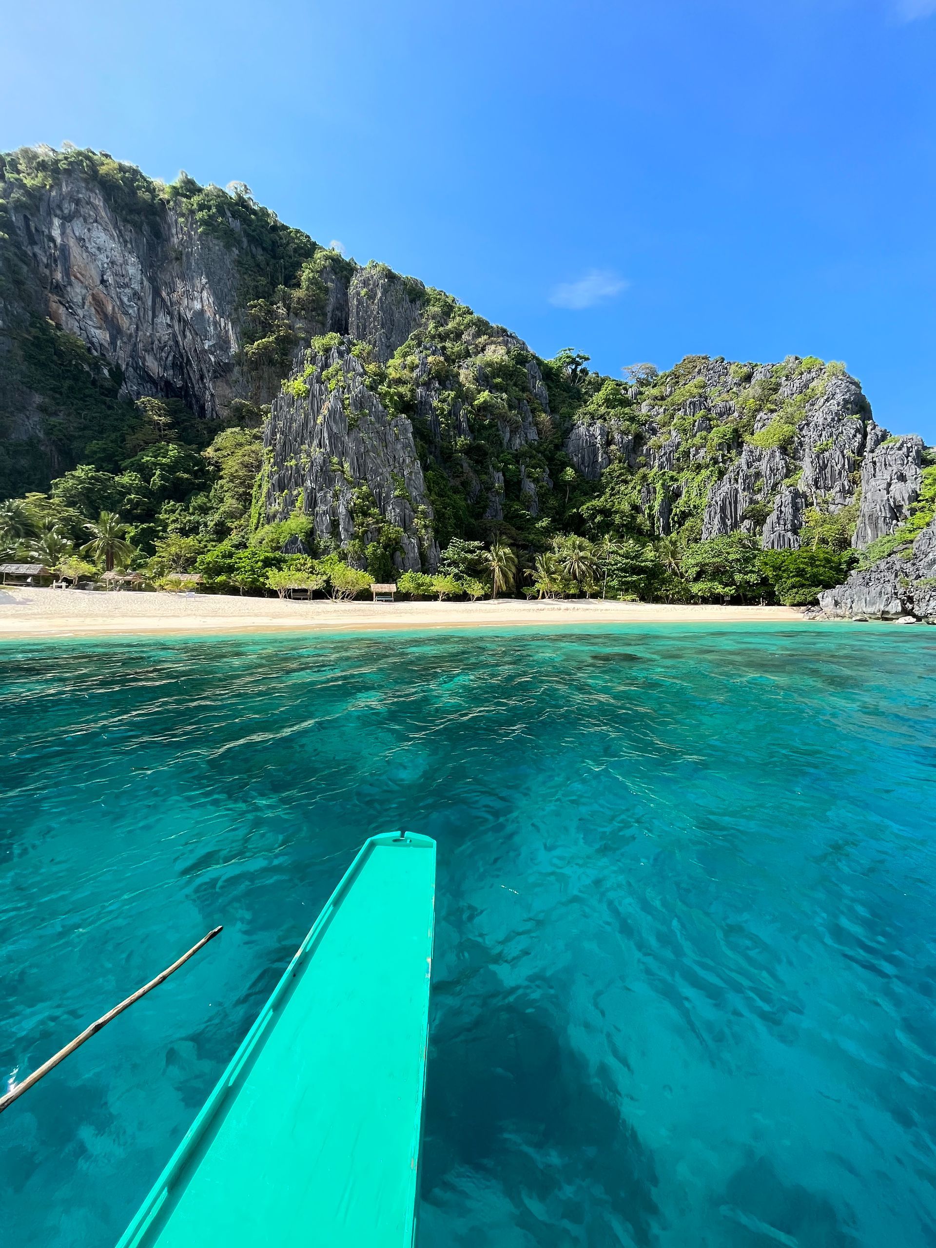A boat is floating on top of a body of water near a beach.