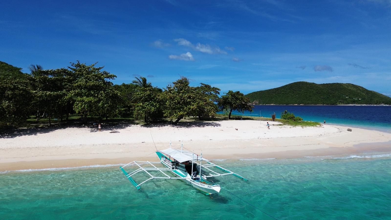 An aerial view of a beach with a boat in the water.