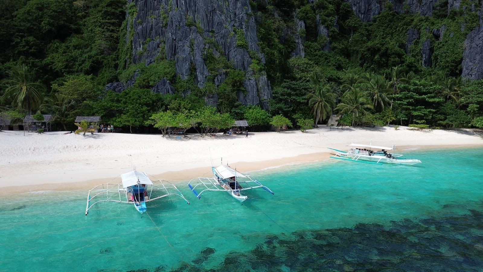An aerial view of a tropical beach with boats in the water.
