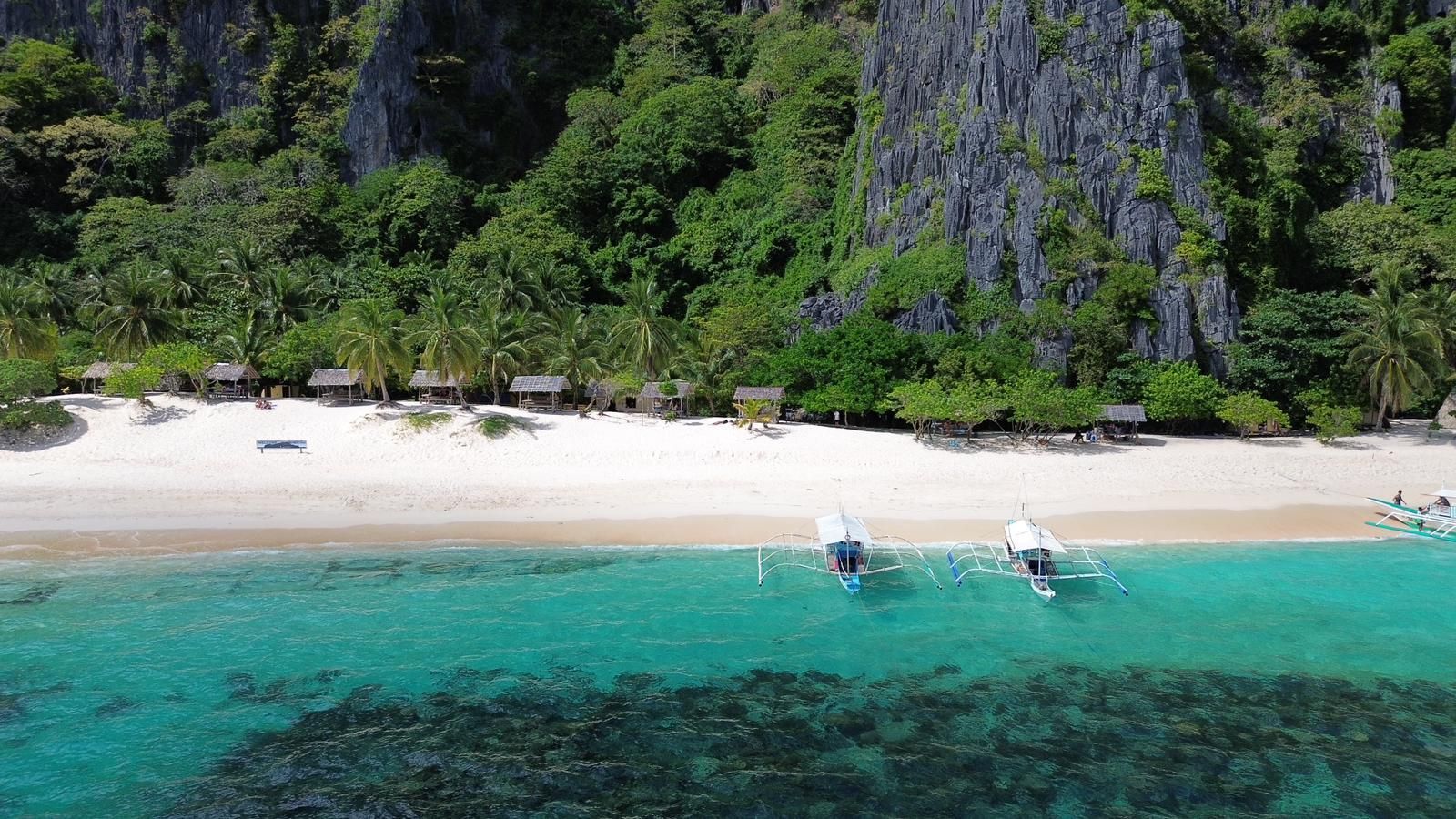 An aerial view of a tropical beach with boats in the water.